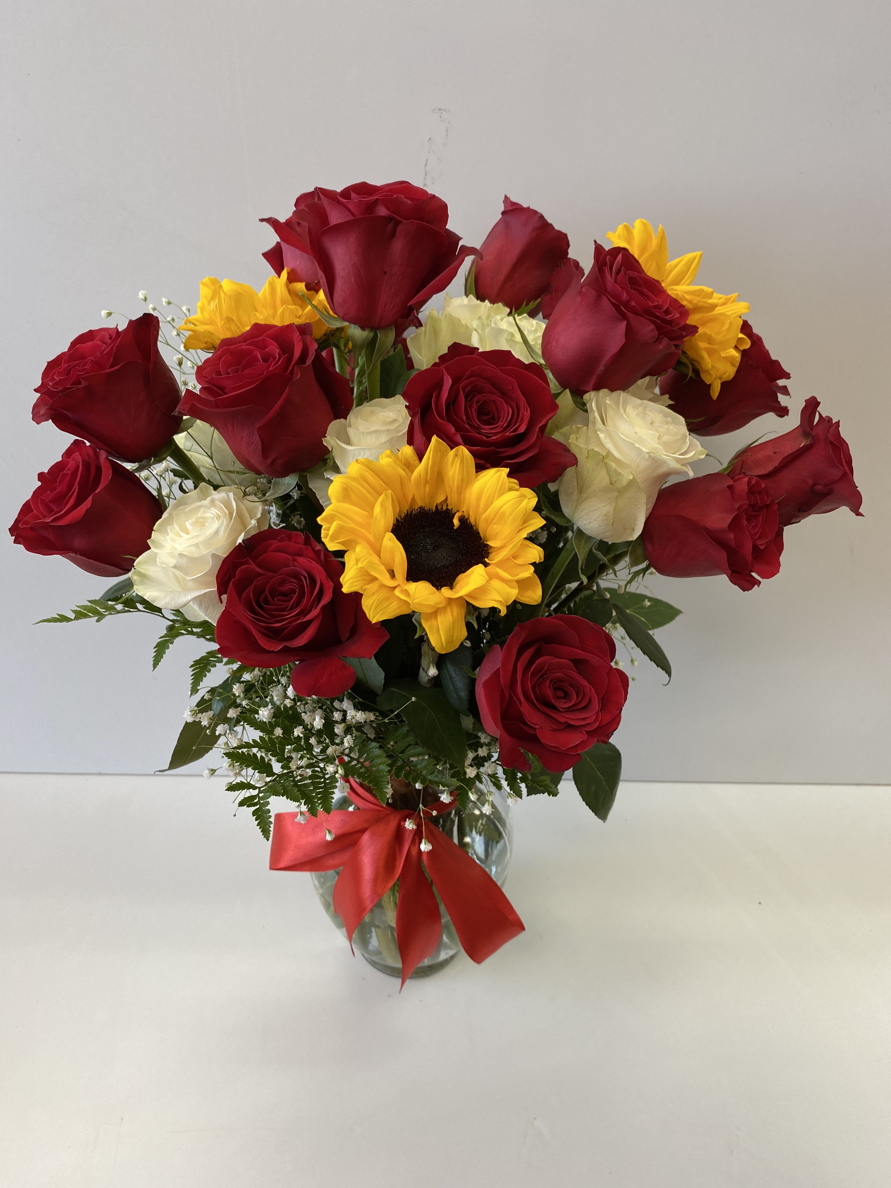 Roses and Sunflowers  - 14 Red Roses, 6 white roses, 3 Sunflowers, with baby breath and greenery; everything is harmoniously combined in a clear vase, with outstanding ribbon bow .
