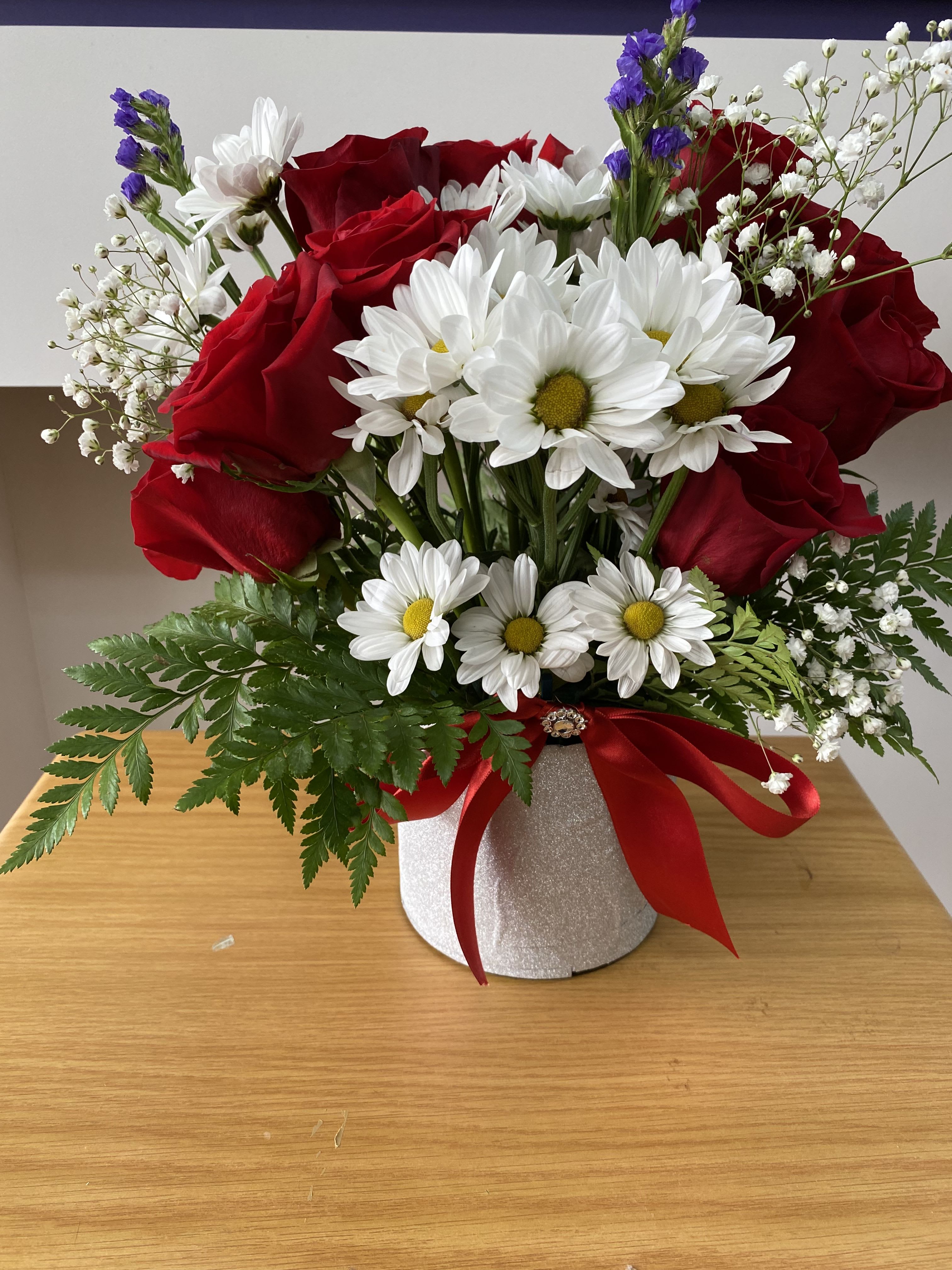 Daisies and Roses  - 9 Red roses, some white daises, baby breath , and greenery, leatherleaf in a vase , everything Arranged harmoniously to form an elegant design.