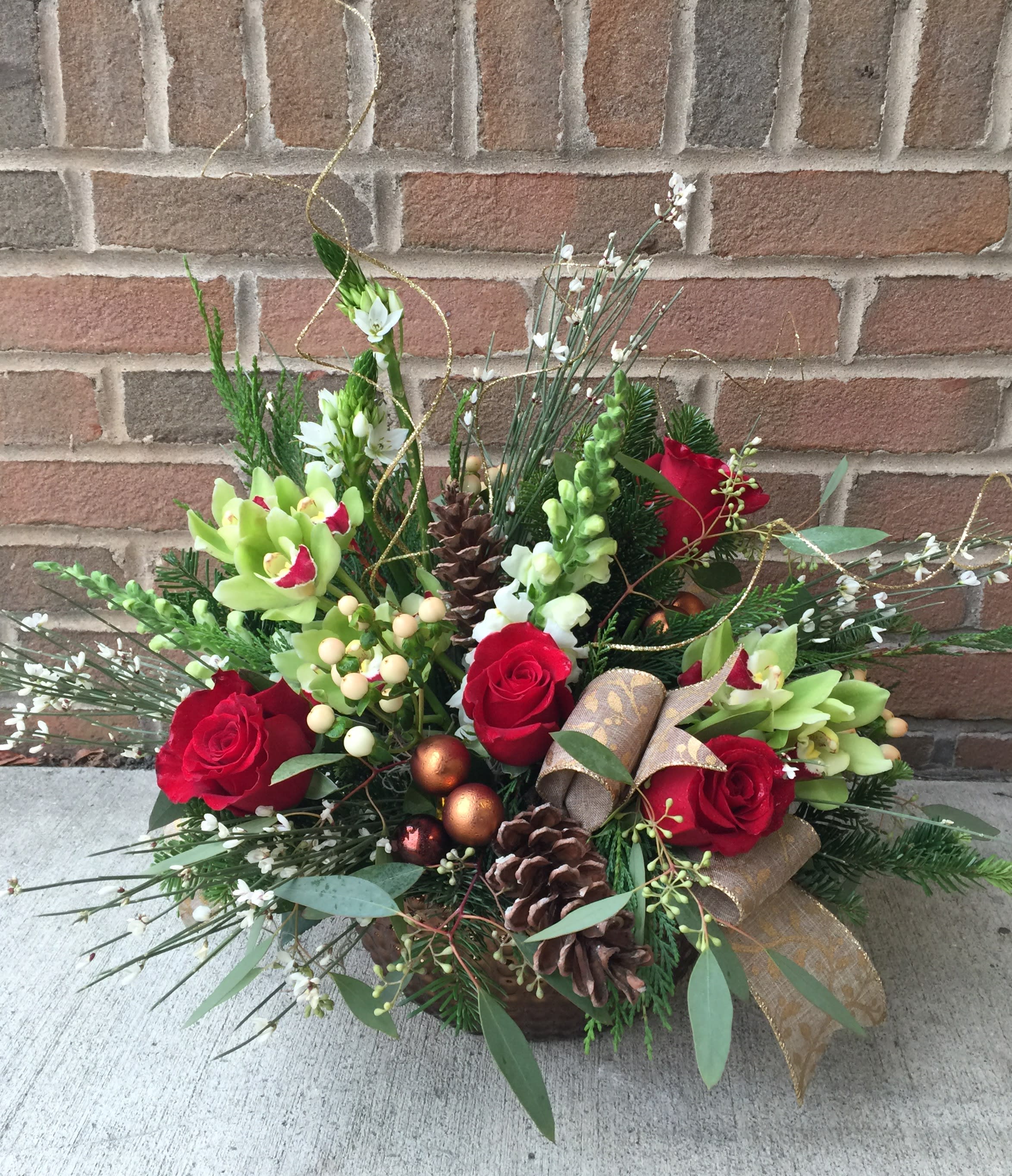 Extravagance - A gorgeous combination of higher end, unique blooms along with fragrant evergreens in a low dish. The design is finished with holiday trim. (Flower varieties may vary dependent on weekly product but the effect is always lovely and elegant.)