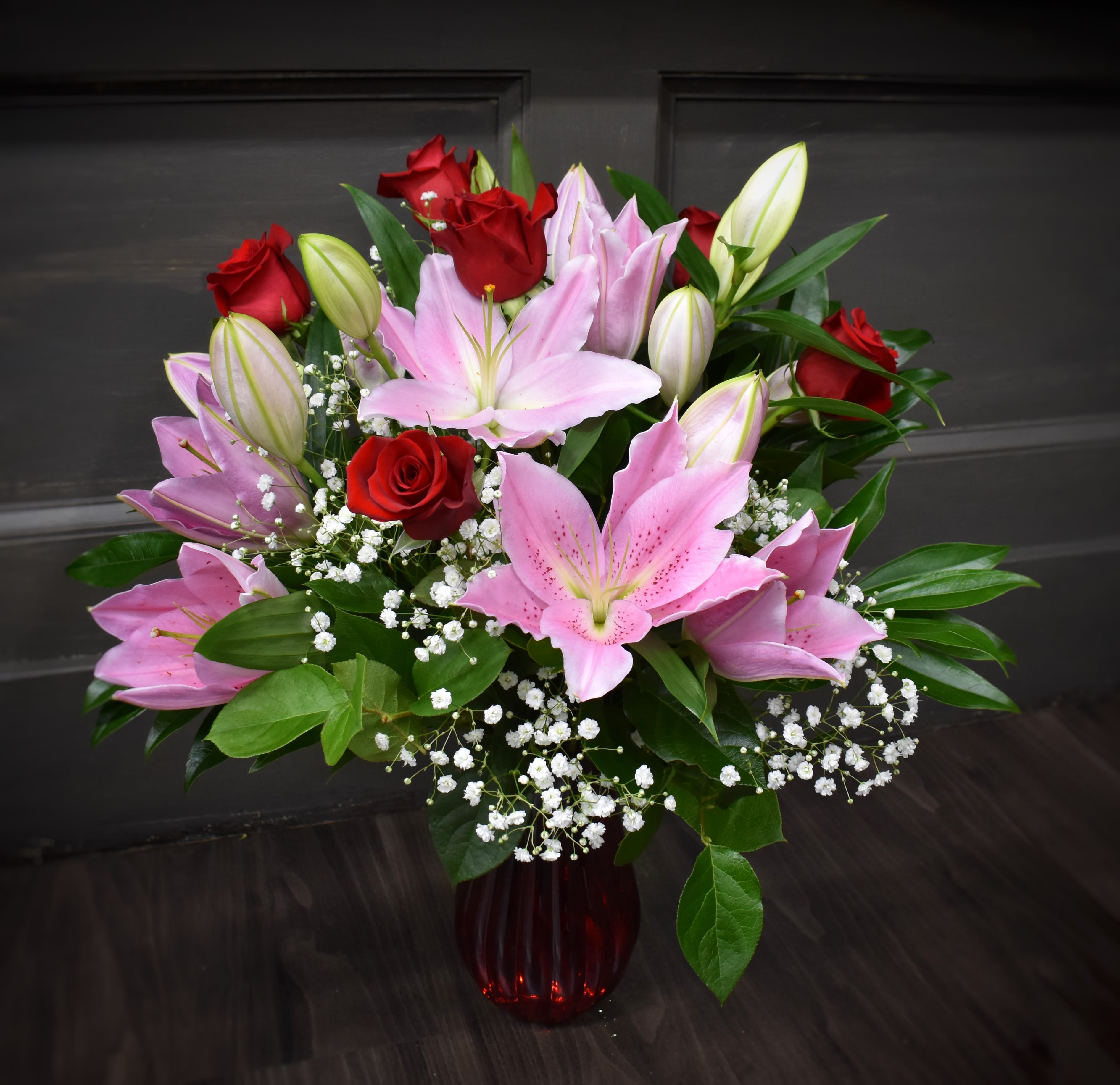 Roses and Lilies Deluxe - One of our most popular bouquets! We've combined 6 long stem red roses along with 6 stems of fragrant MN grown lilies, designed in a ruby red vase with assorted foliages and babies breath for the accent flower.