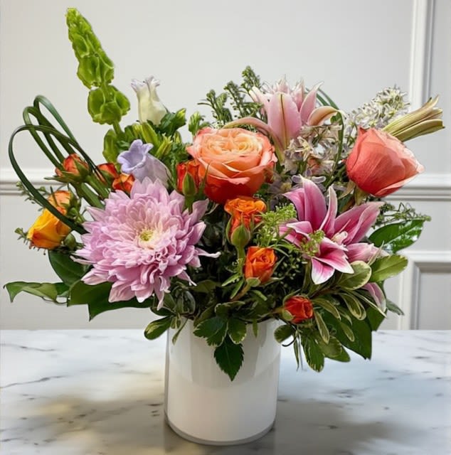 Flare &amp; Bloom  - A vibrant and dynamic arrangement featuring a lively mix of peach, pink, and orange blooms. Presented in a crisp white vase, this design brings warmth and energy with a modern flair—perfect for adding a bold touch to any occasion.