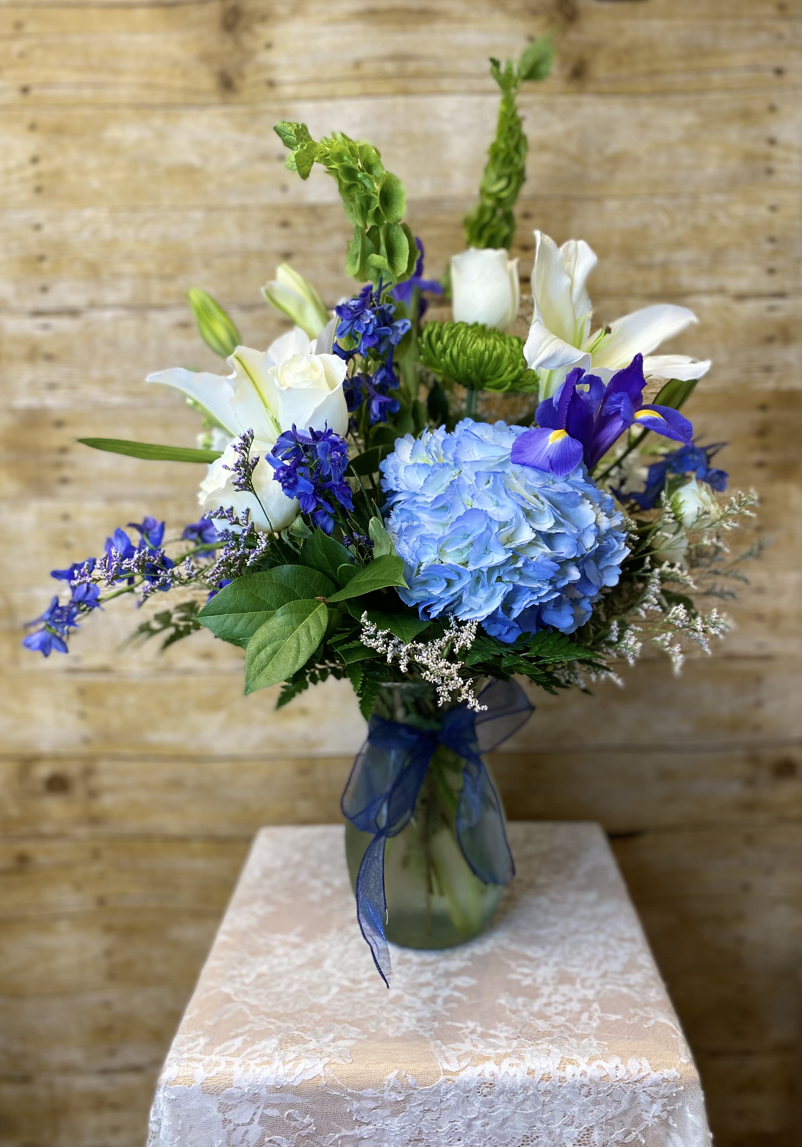 Breezy by the Sea by BloomNation™ - This arrangement contains delphinium, bells of ireland, asiatic lilies, hydrangea, and other seasonal blooms. It is a great gift for a birthday, get well, for wishing someone a fresh start.