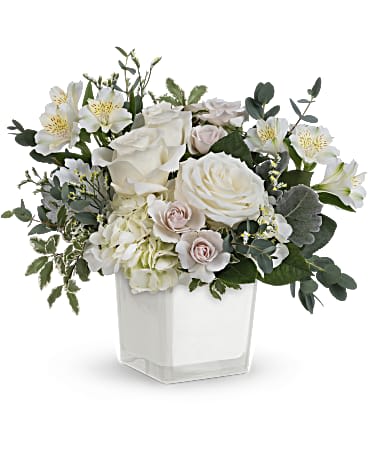 Peaceful Clouds - As serene as soft white clouds floating in a crisp blue sky, this elegant white rose bouquet in a simple glass cube brings peace and beauty to any occasion. This peaceful arrangement includes white hydrangea, white roses, white spray roses, white alstroemeria, dusty miller, white limonium, and premium greens. Delivered in Teleflora's Color Splash cube. Approximately 10" W x 10" H