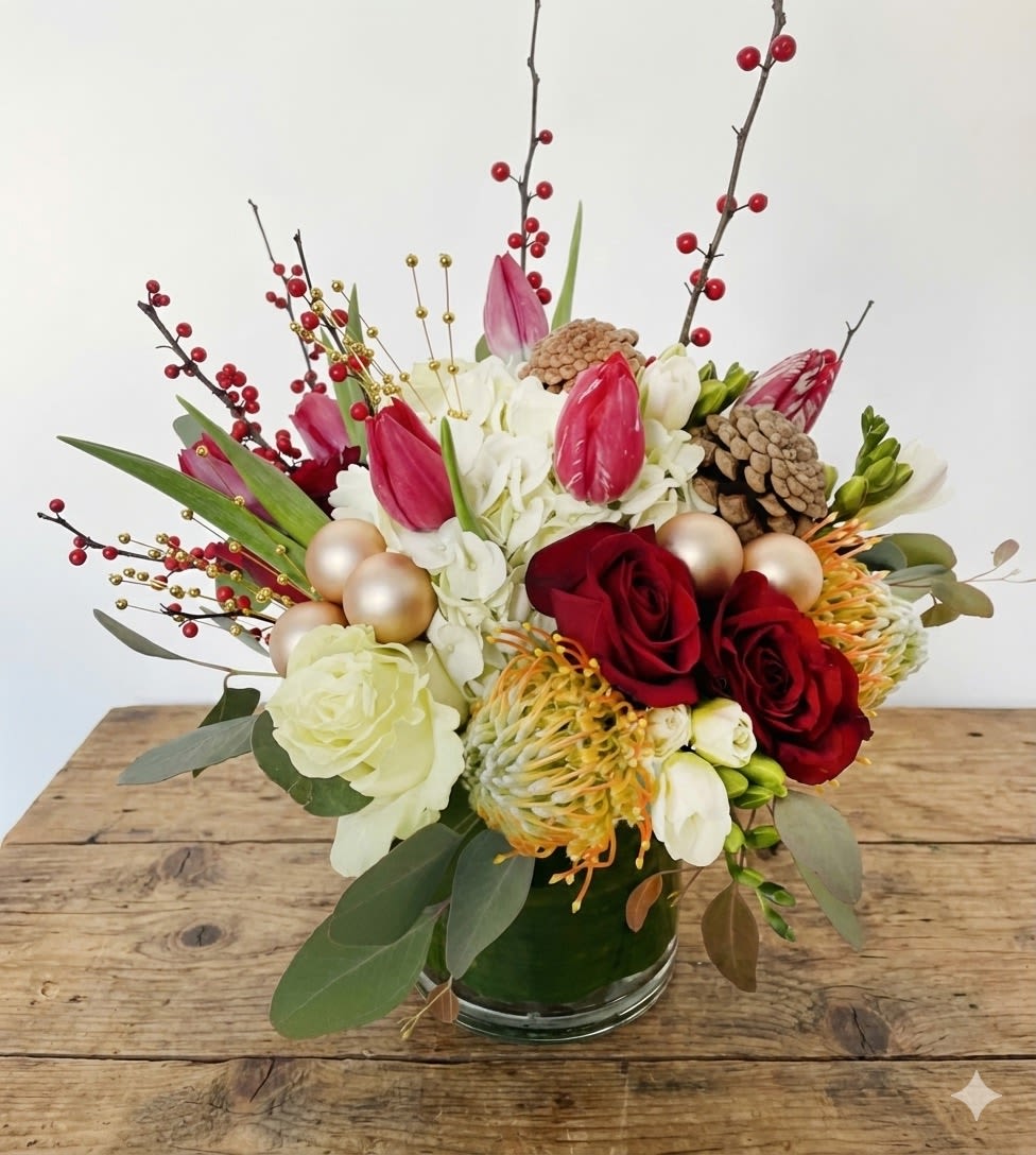 Wish you a happy holiday - Festive, joyful, and full of seasonal charm, Wish You A Happy Holiday is a cheerful arrangement designed to celebrate the magic of the holidays. Rich red roses are beautifully paired with elegant tulips, creamy white blooms, textured pincushion protea, fresh greenery, and playful berry accents. Gold ornament details and natural pinecones add a warm, celebratory touch, all arranged in a clear glass cylinder vase for a polished finish.  Perfect for holiday gifting, seasonal celebrations, or as a welcoming centerpiece, Wish You A Happy Holiday brings color, texture, and festive spirit to any home or office.  Details: 	•	Features red roses, tulips, white seasonal blooms, pincushion protea, holiday berries, pinecones, and fresh greenery 	•	Accented with subtle gold ornament details 	•	Designed in a clear glass cylinder vase 	•	Lively holiday palette with rich textures and elegant height 	•	Designed by Sunny Florists  Please note: Flower varieties and decorative accents may vary slightly due to seasonal availability, while maintaining the overall color palette and design style.