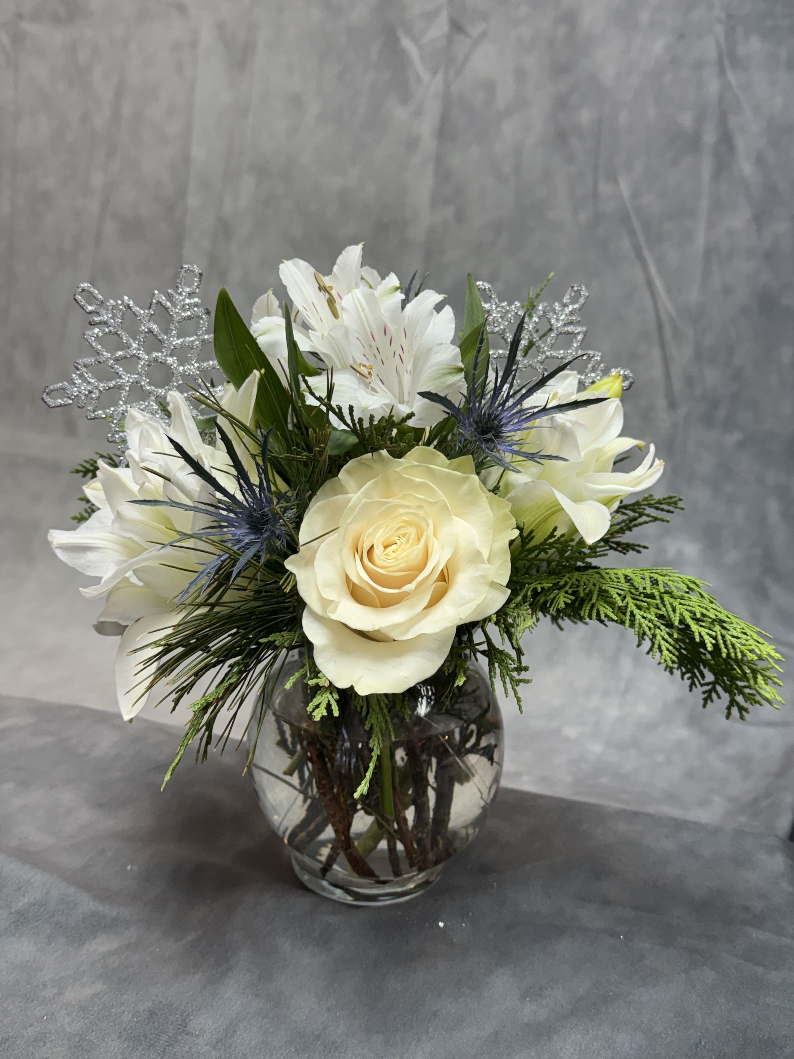 Winter Snowfall Posy - A timeless winter arrangement featuring creamy white roses, delicate alstroemeria, frosted accents, and lush seasonal greens for a soft, snowy elegance.