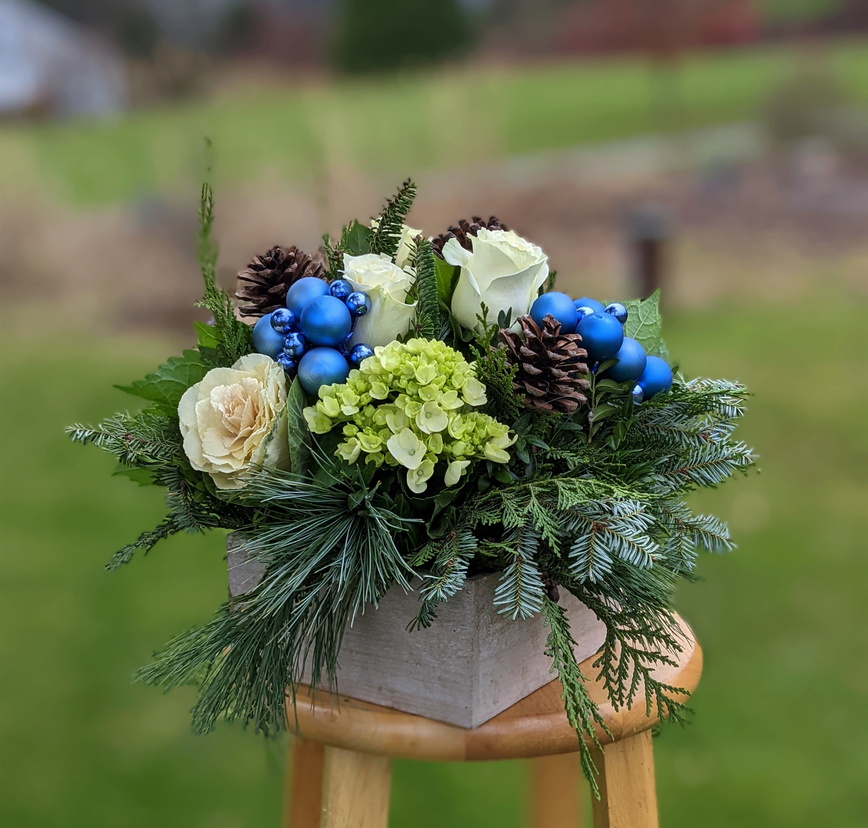 Blue Ice - Our rustic whitewashed box overflows with seasonal flowers and fragrant greens. Holiday accents add a bit of sparkle, and cool blue mini-lights are available as an add-on.