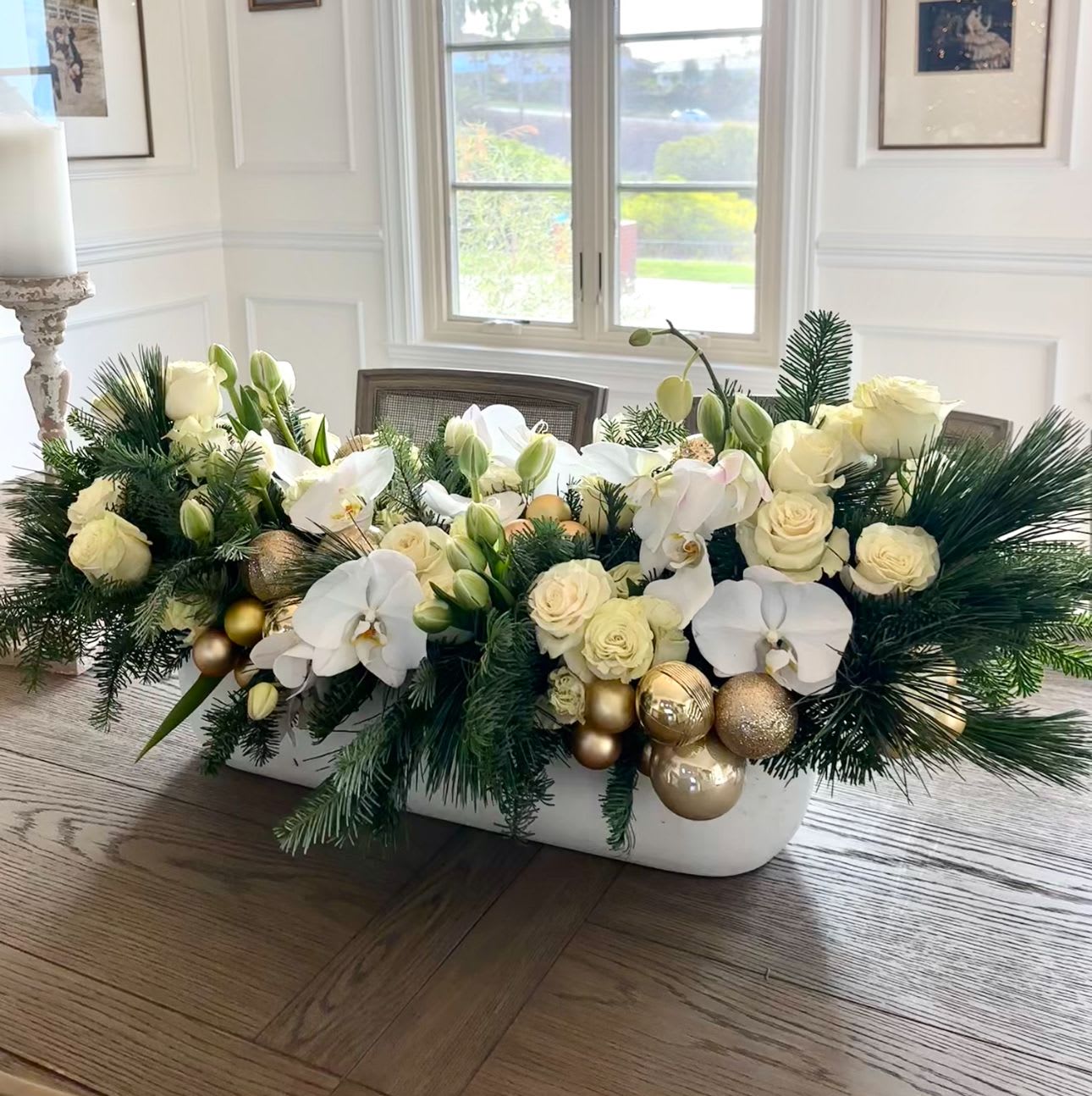 Holiday White Centerpiece Long and Low - A stunning compilation of roses, orchids and assorted luxury white florals, with gold ornaments in a long and low vessel, perfect for long tables surrounded for family gathers, o to send as a gift from far away. 