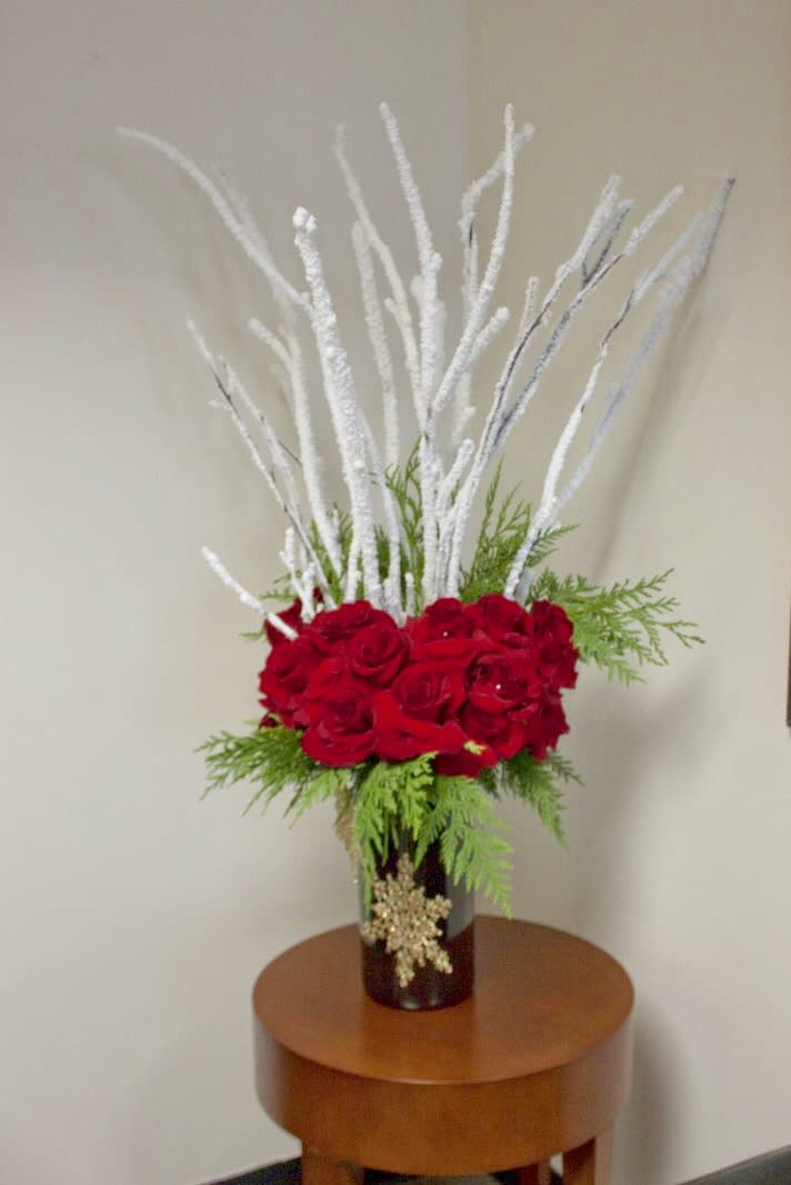 Roses and Elegant Holiday Branches  - On a bed of Cedar and Hydrangeas, this towering design is sure to stand out this holiday. With an abundance of Red Roses in a glass vase with frosted branches