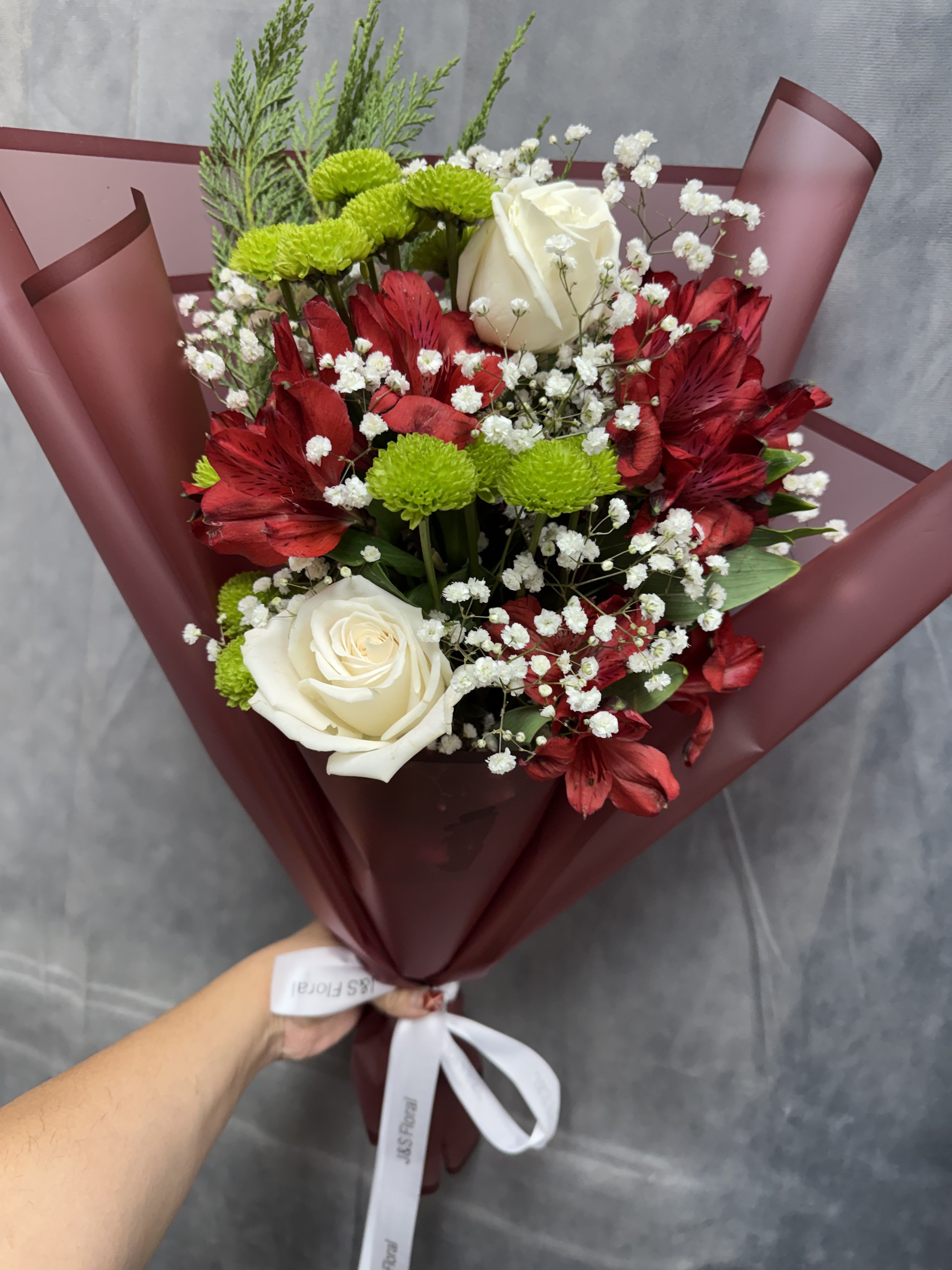 Holiday Harmony Bouquet  - A festive blend of classic elegance and seasonal cheer, featuring rich red blooms, creamy white roses, fresh evergreen accents, and delicate baby’s breath. Perfect for spreading warmth, joy, and holiday magic to someone special. 