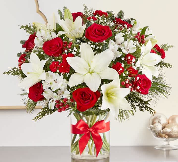 Fields of Europe Christmas LUXE - Our best-selling Christmas bouquet, in a newly designed luxury styling. This generous gathering of red and white blooms is accented by lush greenery all around. Designed in a classic glass vase finished with a red bow, our abundant arrangement captures the festive beauty of the holiday season with every elegant detail.