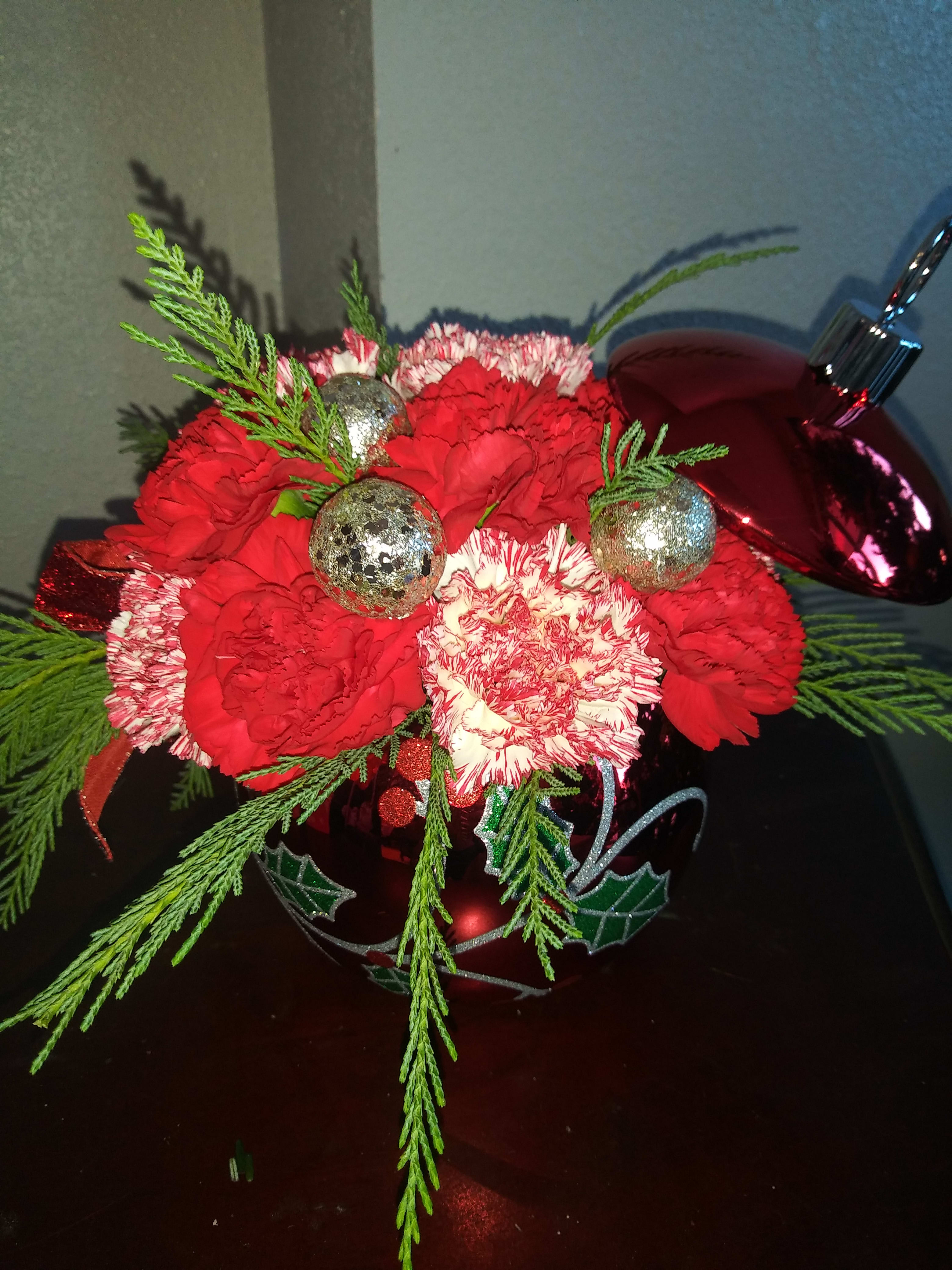 Christmas Holiday Ornament - This Holiday Christmas Ornament has the freshest Christmas greenery with the freshest seasonal flowers such as carnations, roses, and hypericum. Adorned with festive plastic ornaments, this ceramic holiday ornament arrangement is perfect for any desk or fun holiday get togethers. 