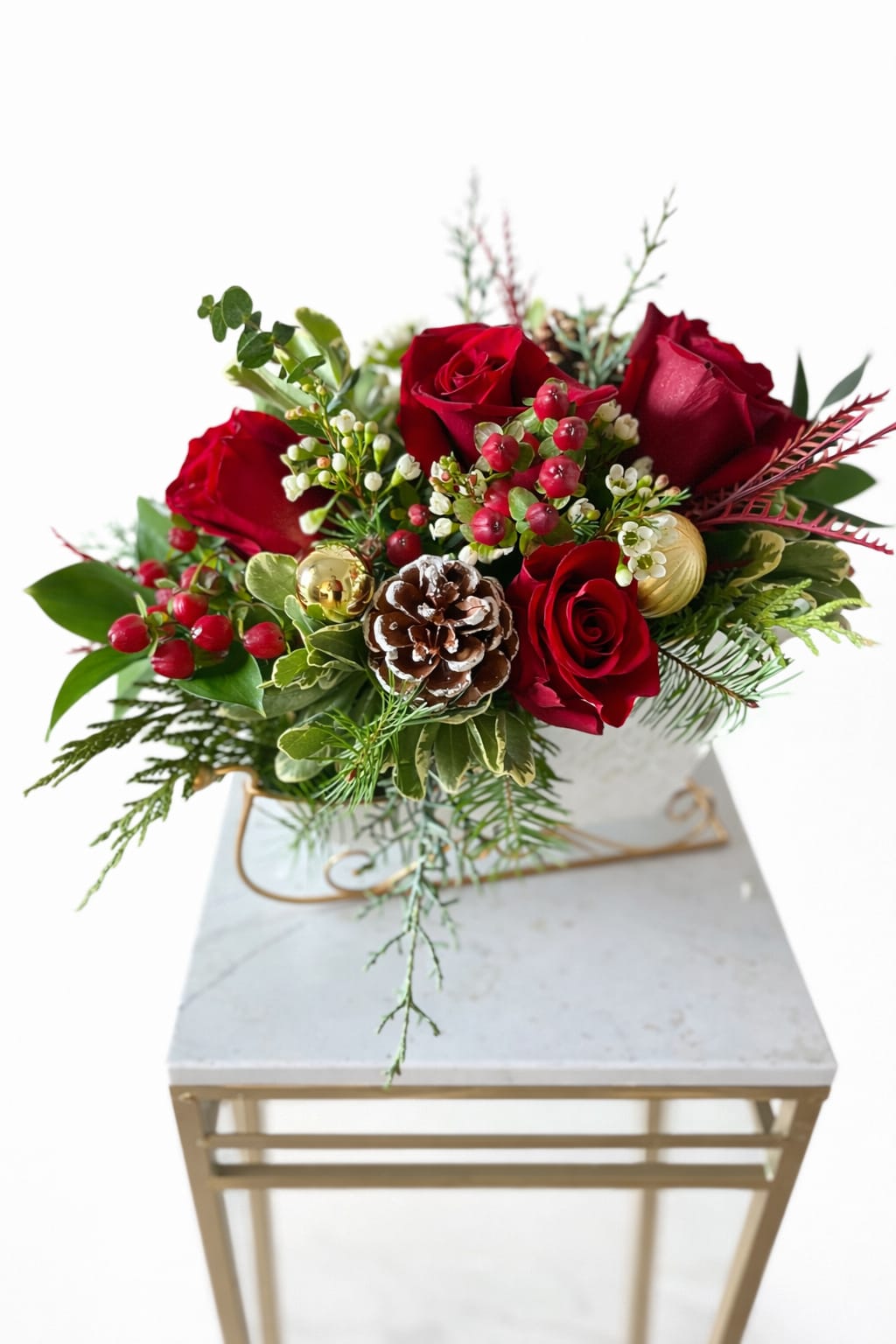 Classic Crimson Christmas - Celebrate the season in timeless style with our classic Crimson Christmas Arrangement. Featuring luxurious red roses, festive winter greenery, frosted pinecone accents, and vibrant red berries, this elegant design captures the warmth and beauty of Christmas. Perfect for holiday tables, gifting, or seasonal décor, it brings classic Christmas charm into any space.