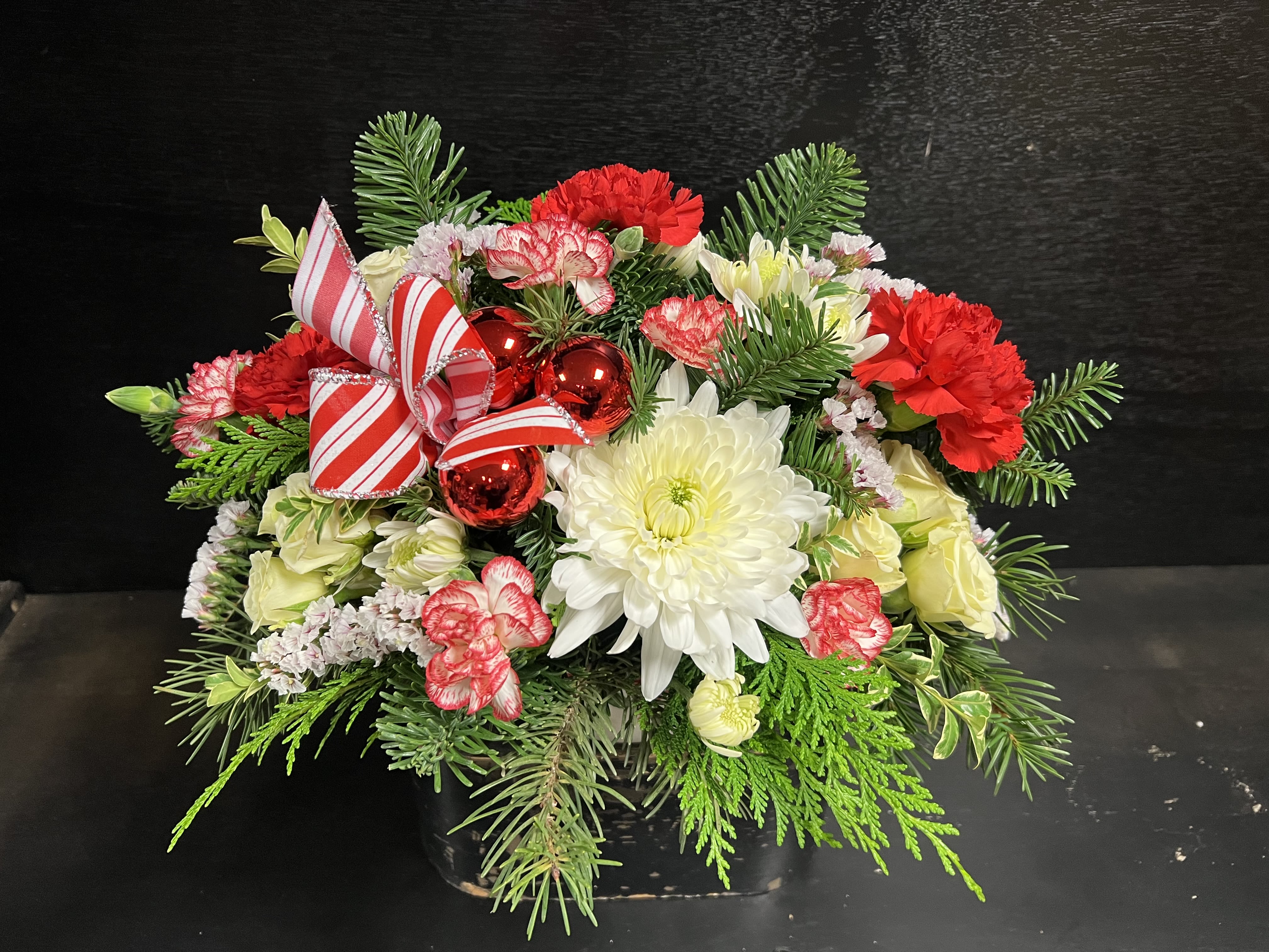 Small Christmas Centerpiece  - This cute small centerpiece is built in a Christmas bowl showcasing various Christmas greens, mini carnations, spray roses, static, and chrysanthemums. 