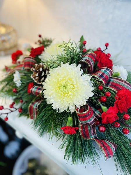 Country Christmas - A beautiful, long lasting centerpiece with a rustic country feel! This design features tartan ribbon, snow tipped cones, white disbuds, red carnations and festive berries. 