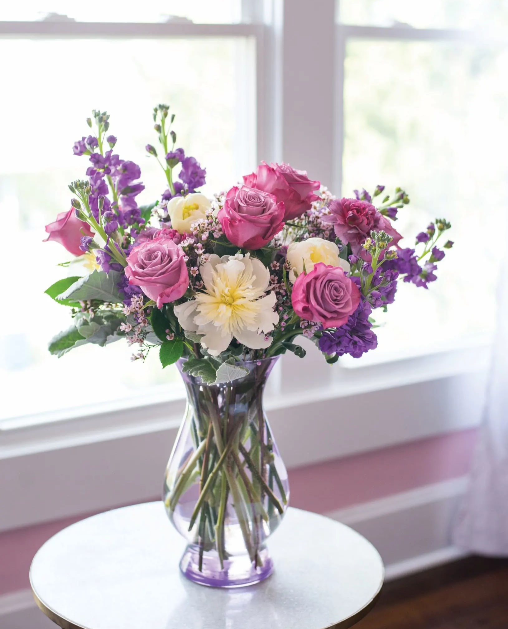 Violetta – Lavender &amp; Ivory Floral Arrangement - A softly romantic floral arrangement designed in lavender, ivory, and violet tones, featuring premium seasonal blooms with graceful movement and layered texture. Styled in a clear glass vase for an elegant, airy presentation.  Perfect for birthdays, anniversaries, sympathy gestures, or refined everyday gifting. Available for delivery in DeLand, Lake Mary, Winter Park, Sanford, Altamonte Springs, Deltona, and surrounding Central Florida areas. Flower varieties and vase style may vary slightly based on availability while maintaining the overall palette, balance, and value.