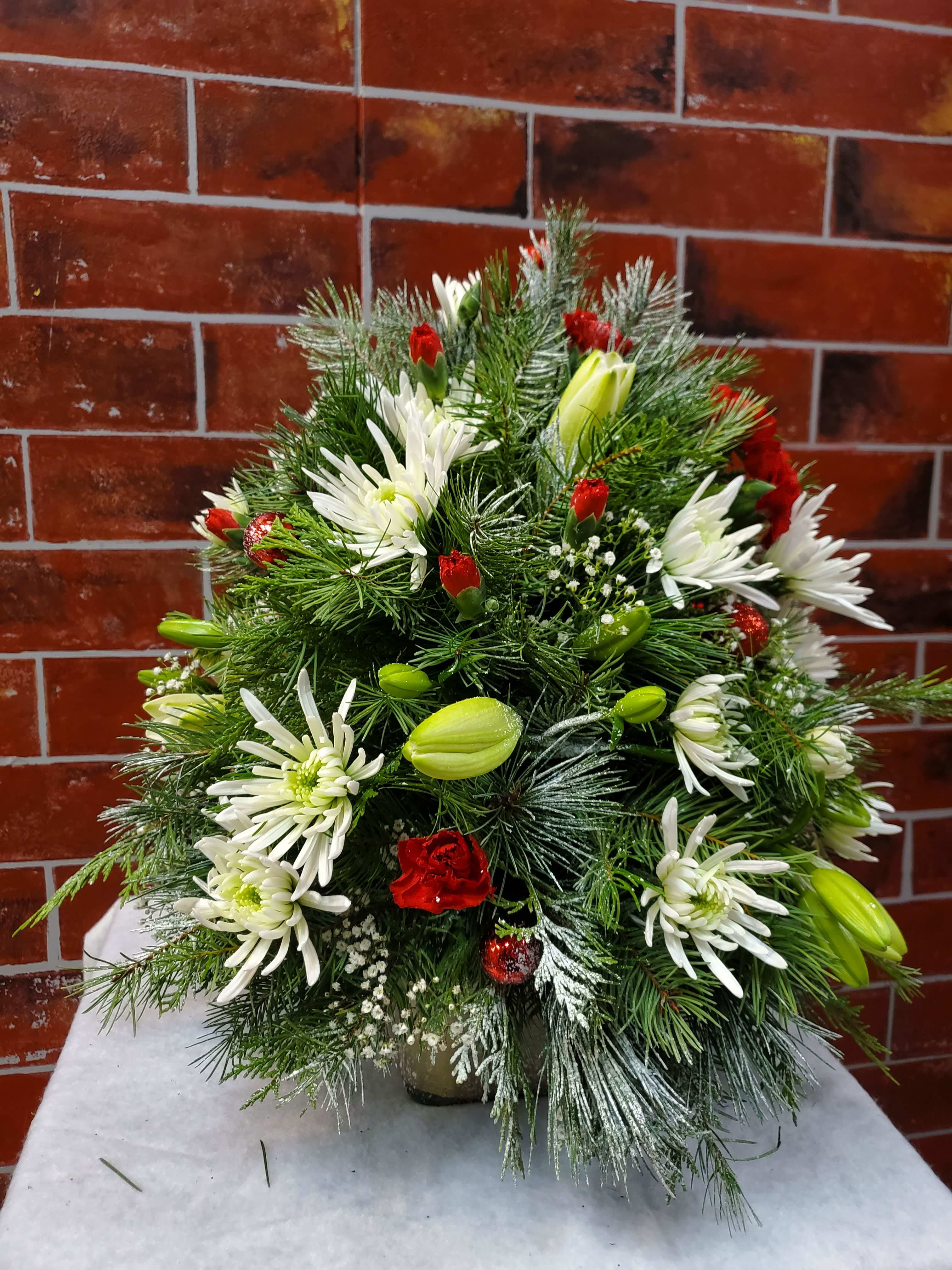 Christmas Tree Arrangement  - It is a bouquet that is shaped like a charismas tree   *Some stages of flower life may vary. (Example: Lilies may be more open than imaged.)  Flower shortages and product availability means that some substitutions will apply. Value will always be filled.  This bouquet might include eucalyptus amongst the greenery. It may be toxic to pets including but not limited to Cats and Dogs if digested.