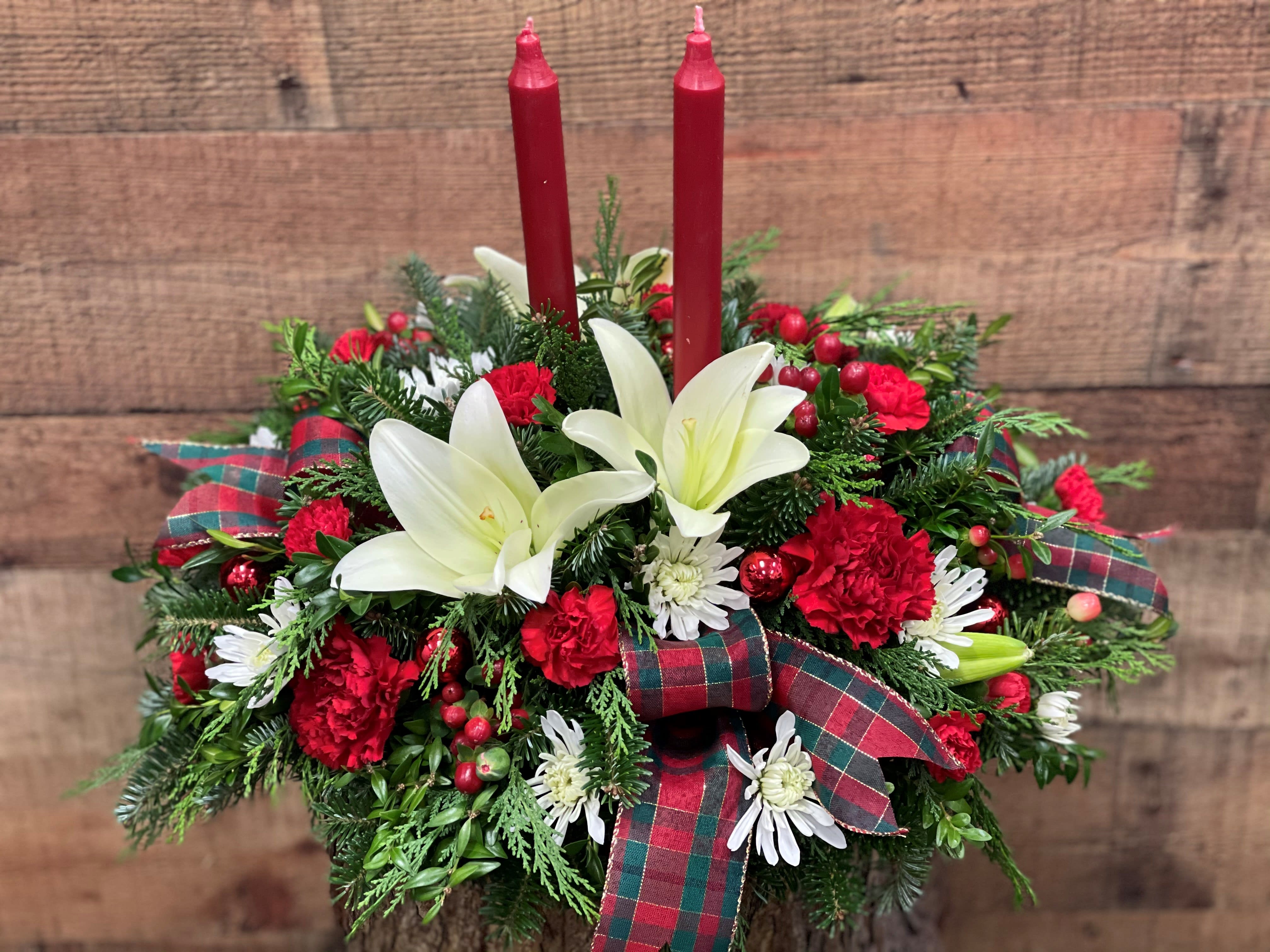 Country Glow Centerpiece - Classic carnations and chrysanthemums paired with elegant lilies are artfully arranged with country plaids and natural cones to add that "home" to your dining table. 