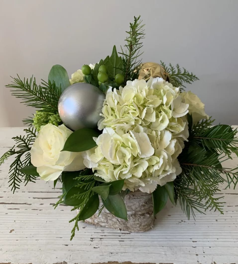 Auld Lang Syne - White and green blooms with Christmas greenery and accents in a 6" vase.  Upgraded versions will feature more flowers.
