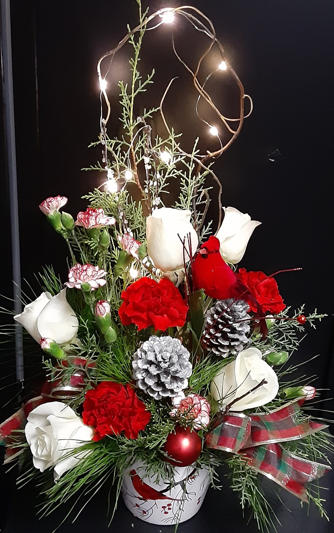 Light Up Christmas!**CONTAINER IS SOLD OUT - Beautiful Christmas lights spread holiday joy far and wide!   Light up Christmas with this bouquet of red and white, roses and carnations, hand-crafted by one of our professional designers and delivered to your loved one.   Order now. Spread Christmas cheer.  Lights have a blinking or solid option.  * We will substitute a red glass cylinder container! 