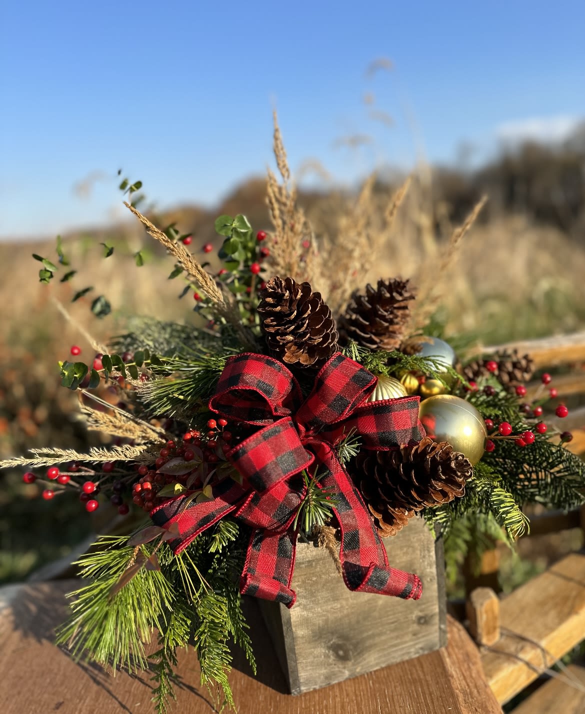 Holly Jolly Arrangement  - Spread holiday cheer with our Holly Jolly arrangement. Designed in a rustic wooden box, this festive display features fresh winter greens, charming holiday accents, and a delightful holiday-themed bow. Perfect for brightening your home or gifting to loved ones, this arrangement captures the heartwarming spirit of the season.