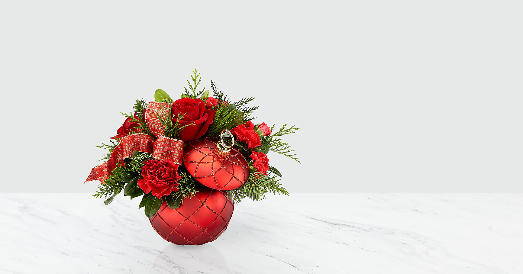 Christmas Magic™ Bouquet - An elegant combination of red roses, carnations and berries, nestled in a bed of Christmas greens, makes for an arrangement with a magical touch. The Christmas Magic bouquet brings this season favorite blooms for the perfect gift for your loved ones this year; the red ceramic ornament vase is a sparkling keepsake.   ITEM #18-C5S