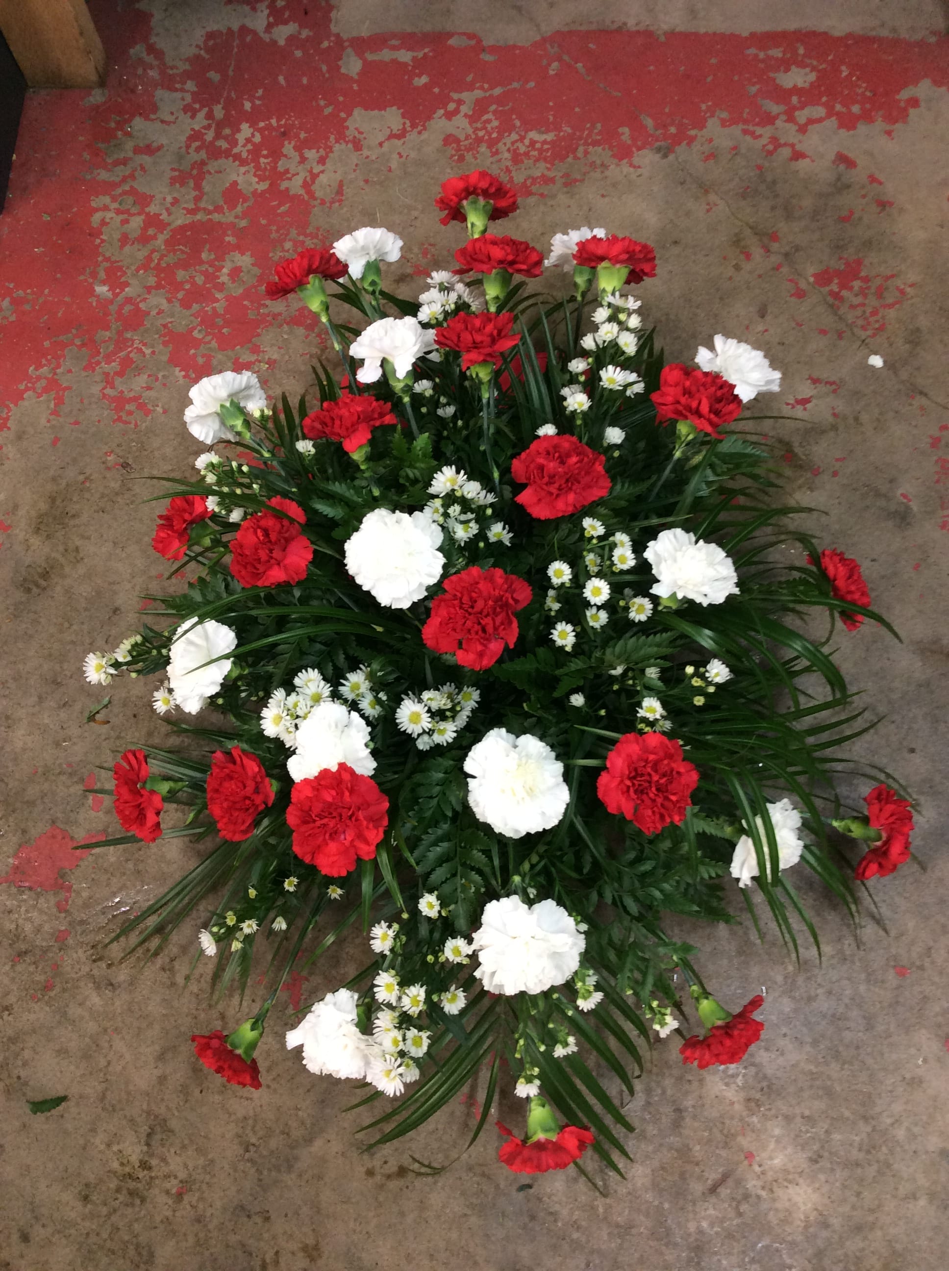 Red and White Carnation Standing Spray - Standing spray with red and white carnations and matching filler. Florals may vary due to availabity while keeping the overall look and feel of the arrangement. 