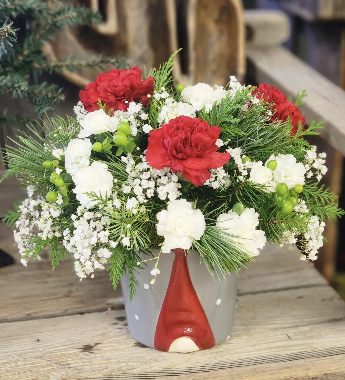 Gnome for the Holidays - Bring a touch of holiday whimsy to any space with this charming ceramic pot featuring a festive gnome motif. Filled with fresh carnations and Christmas greens in classic seasonal colors, this arrangement is perfect for gifting or decorating your home.  Cheerful, cozy, and full of holiday spirit, it’s a delightful way to celebrate the season.