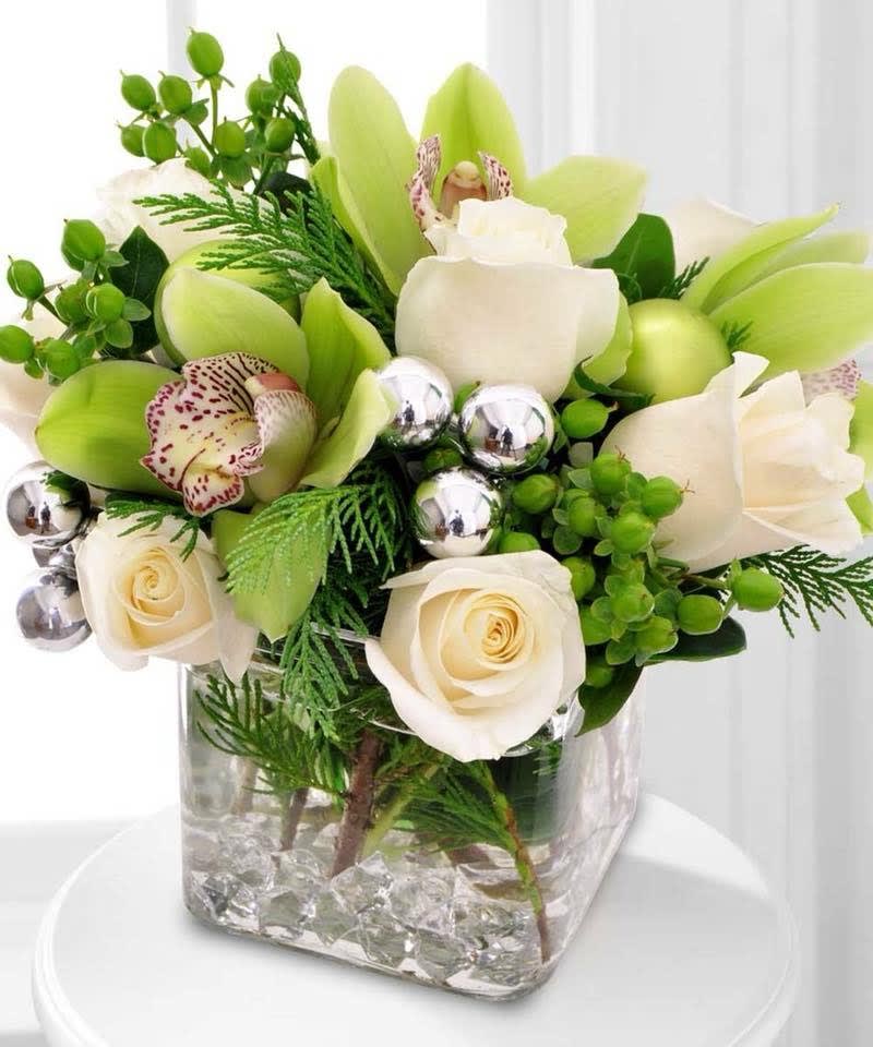 Silver Bells - Silver ornaments and seasonal berries accent this festive holiday design comprised of pure white Roses and green Cymbidium Orchids, with a touch of aromatic greenery.