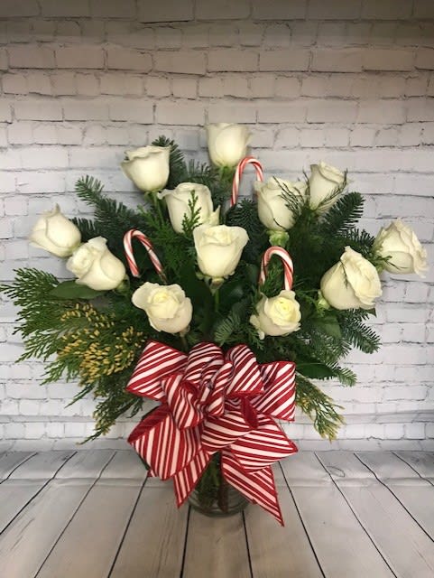 A Peppermint Dozen - Snowy White Roses adorned with Christmas greens and candy canes in a glass vase.
