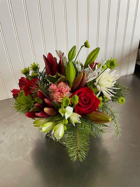 Compacte Designer's Choice - In a low, square, glass vase, this arrangement will include seasonal blooms and greenery which may or may not include the flowers pictured. If you have specific wants for the arrangement please leave a note at checkout and we will try to include your special requests.