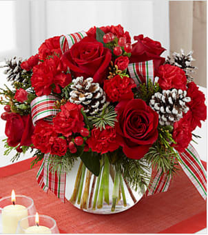 Christmas Peace Bouquet - Christmas Peace Bouquet brings beauty and grace to their home or holiday table with each elegant bloom. Rich red roses are a standout arranged amongst red carnations and mini carnations, red hypericum berries and an assortment of lush holiday greens. Accented with white pinecone pics and a designer ribbon, this fresh flower bouquet is presented in a clear glass bubble bowl vase to create a wonderful Christmas gift for any of the special people in your life. Your purchase includes a complimentary personalized gift message.