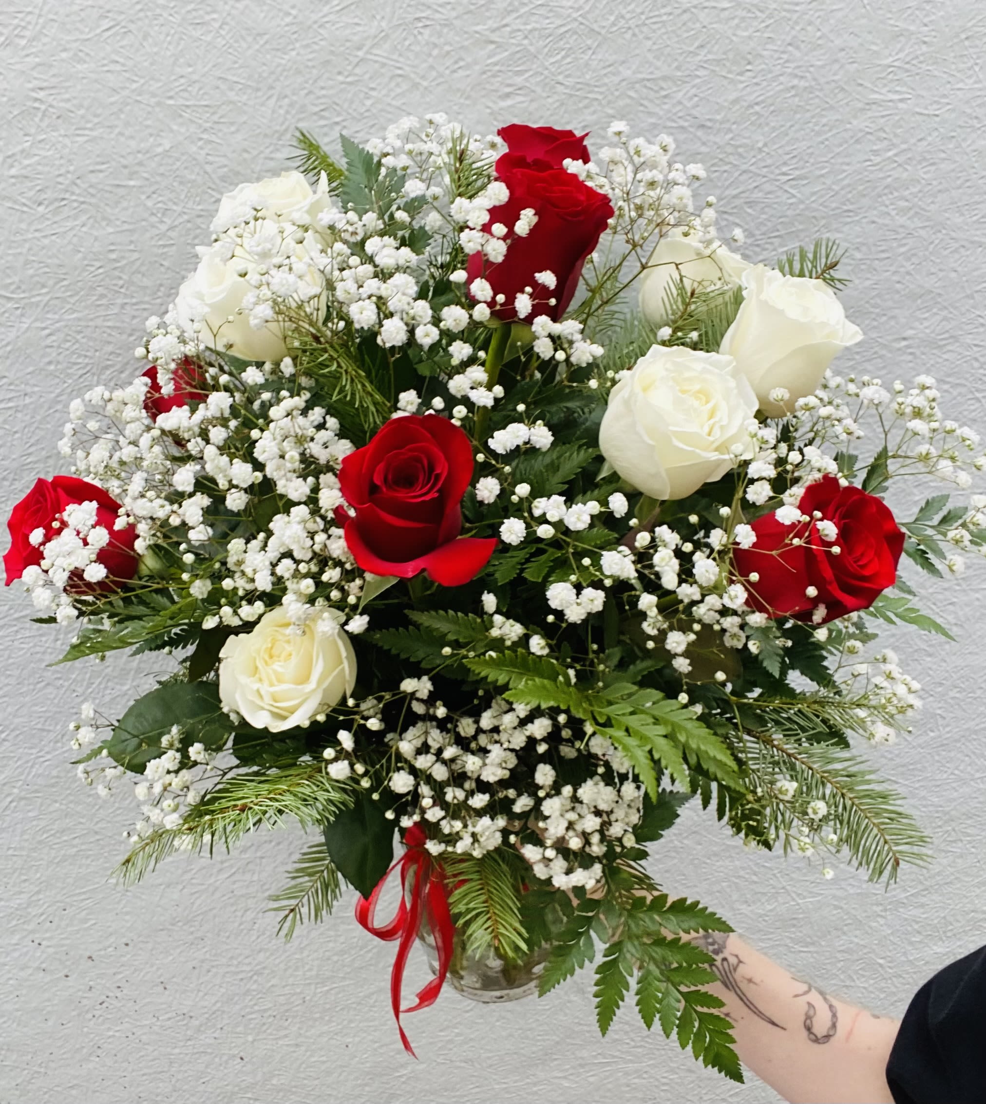 Candy Cane Lane - Half red and half white roses. Candy Cane Lane is a festive stroll through the sweetest sights of the season. This cheerful holiday arrangement features classic Christmas colors of vibrant red and crisp white blooms, accented with lush winter greenery and playful candy cane touches. Designed to capture the joy, magic, and nostalgia of the holidays, it brings a bright pop of Christmas spirit to any home, office, or celebration. Perfect for spreading smiles, gifting loved ones, or adding a whimsical touch to your seasonal décor, Candy Cane Lane is a delightful holiday favorite that feels just like Christmas. 