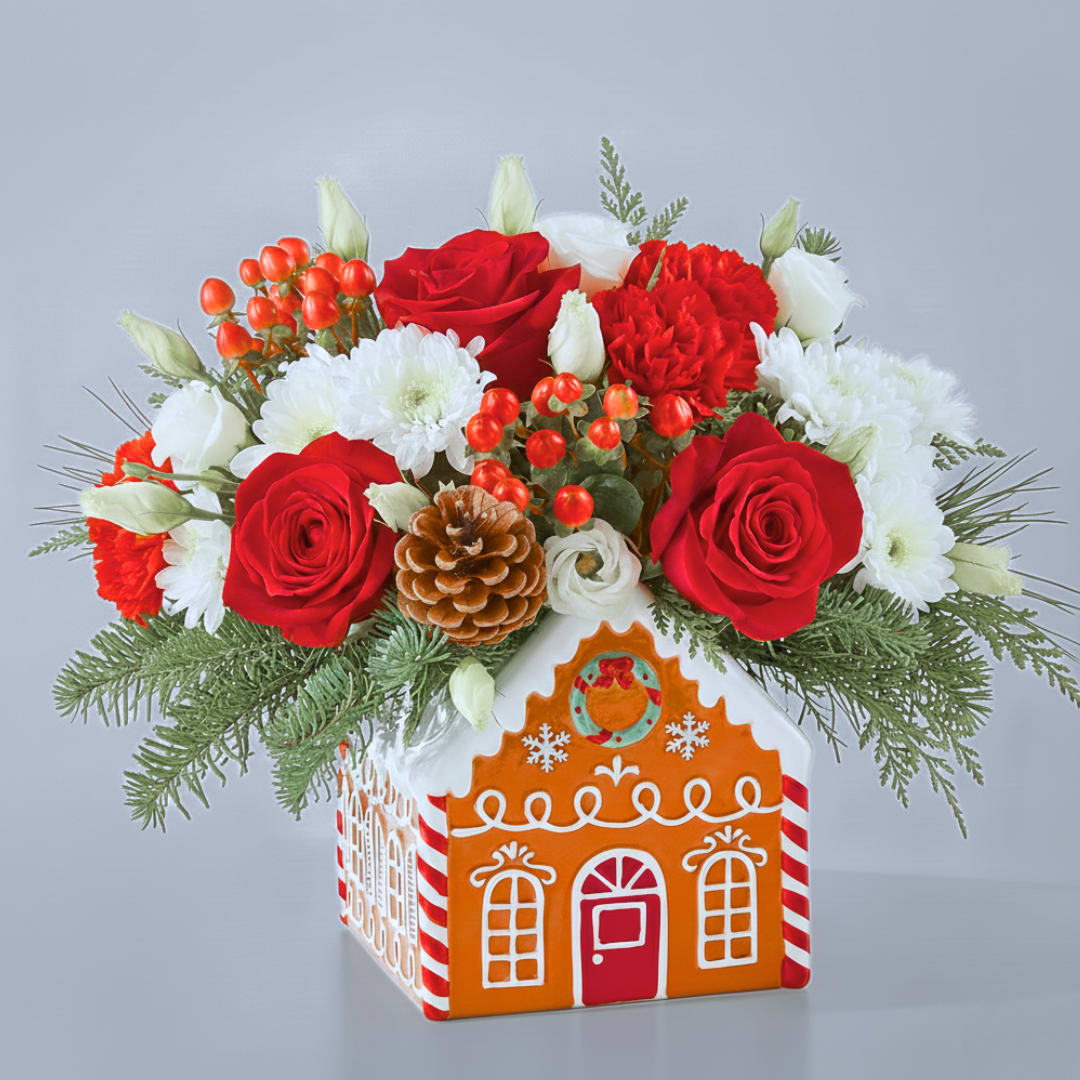 Gingerbread Workshop Bouquet - *** Just a few left! Check out while they're in stock. ***  Capture the spirit of the season with the Gingerbread Workshop Bouquet. This festive arrangement blends velvety red blooms with crisp white stems, nestled in a charming gingerbread house keepsake. It’s a delightful centerpiece designed to evoke the cozy nostalgia of holiday baking and the warm scents of cinnamon and spice. 