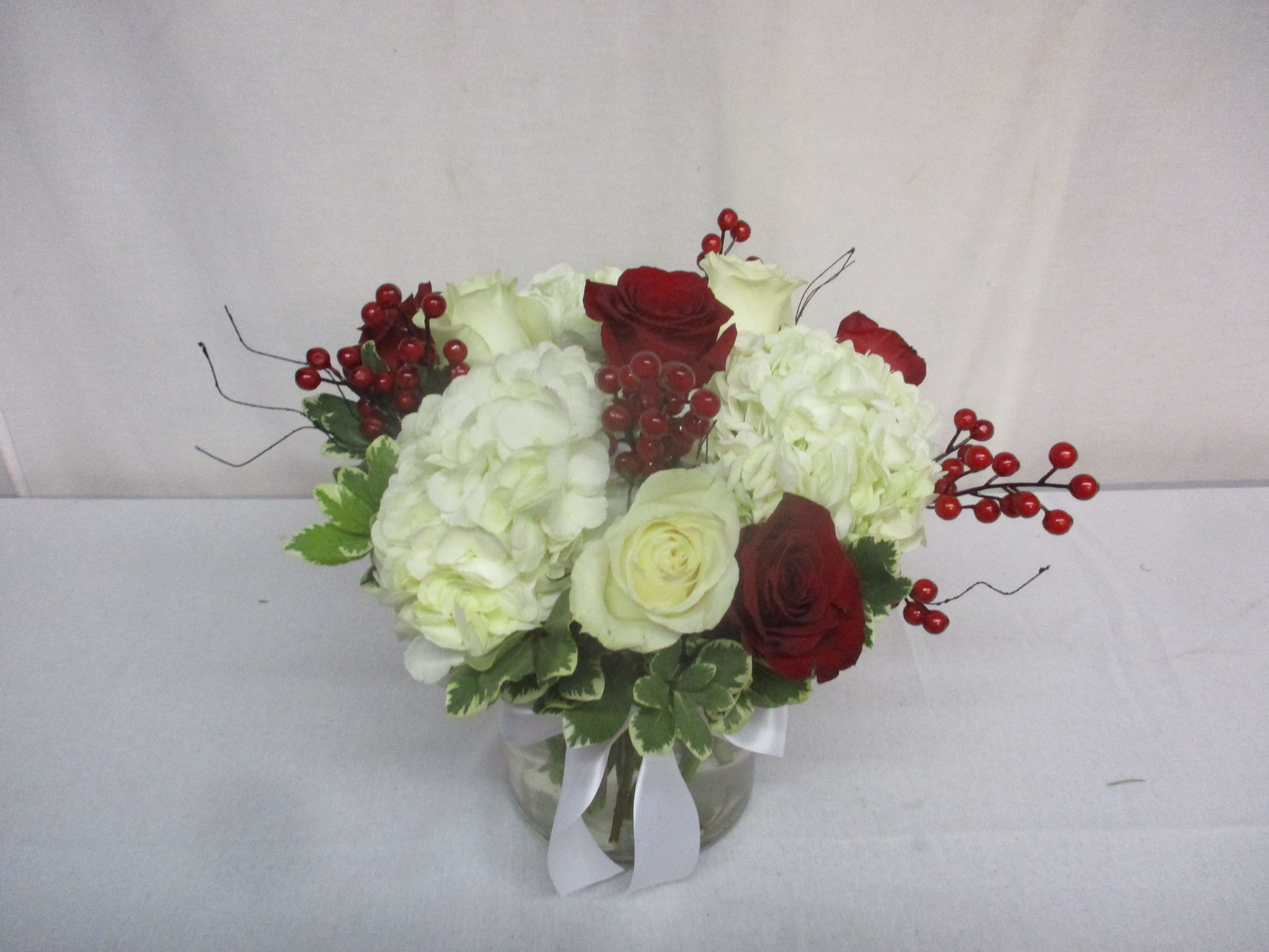 Winterberry Bouquet - Beautiful white hydrangea interspersed with red and white roses and accented by berry sprays - a perfect display for any Christmas gathering.