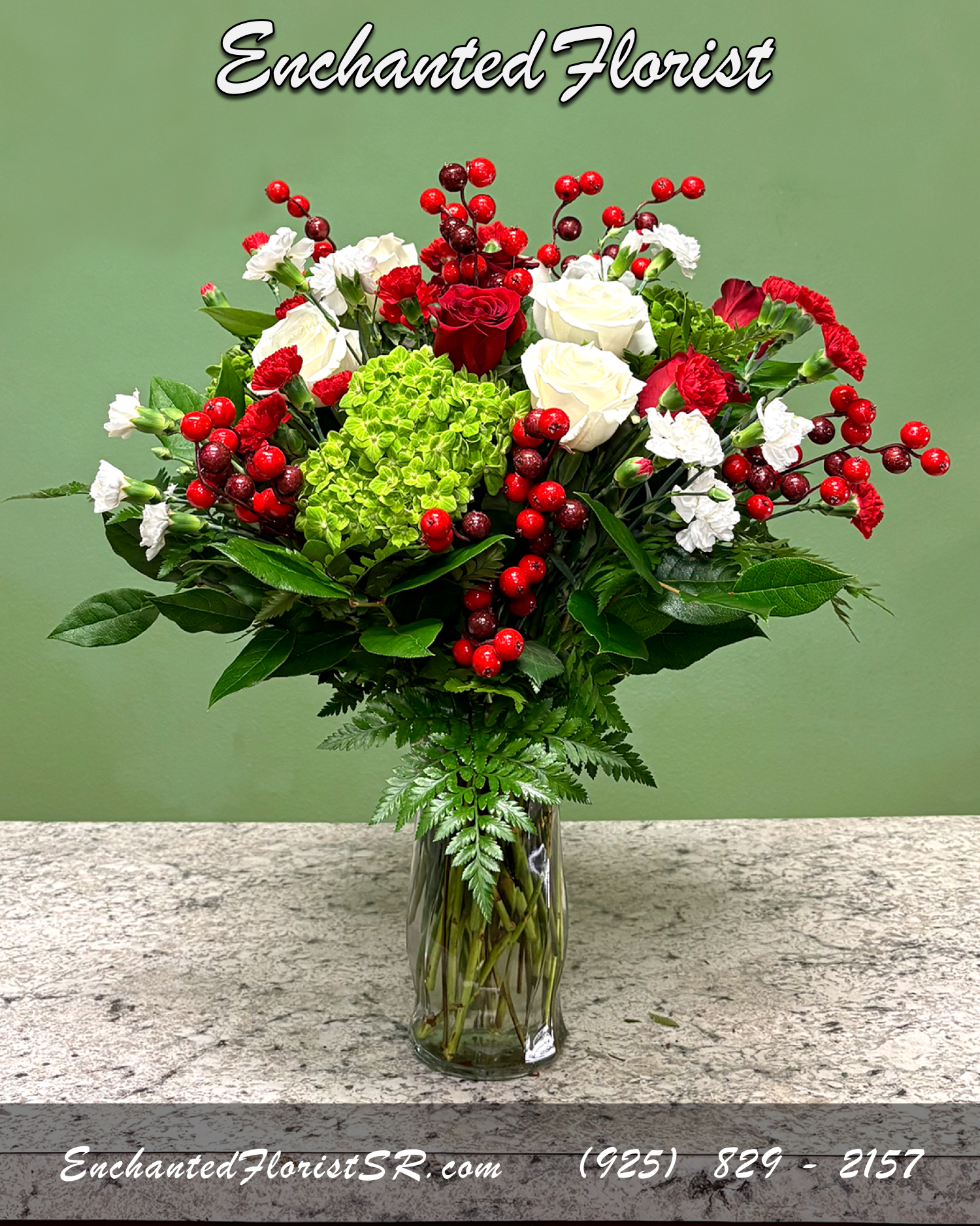 Very Merry - Holiday Arrangement - A mixed arrangement that celebrates the holiday spirit, showcasing a red, white and green palette across a variety of blooms. Featuring roses, carnations, and hydrangeas. Accented with lemon leaves, leather fern, and seasonal decor. Presented in a 'crystal' clear glass rose vase.  Perfect for celebrating the holidays, adding a touch of natural holiday color to any space, or expressing heartfelt sentiments to someone special.  Arrives In: Clear glass cylindrical vase  Orientation: Any-Sided  Approximate Dimensions: 24" Tall 14" Wide 8.75" Vase Height