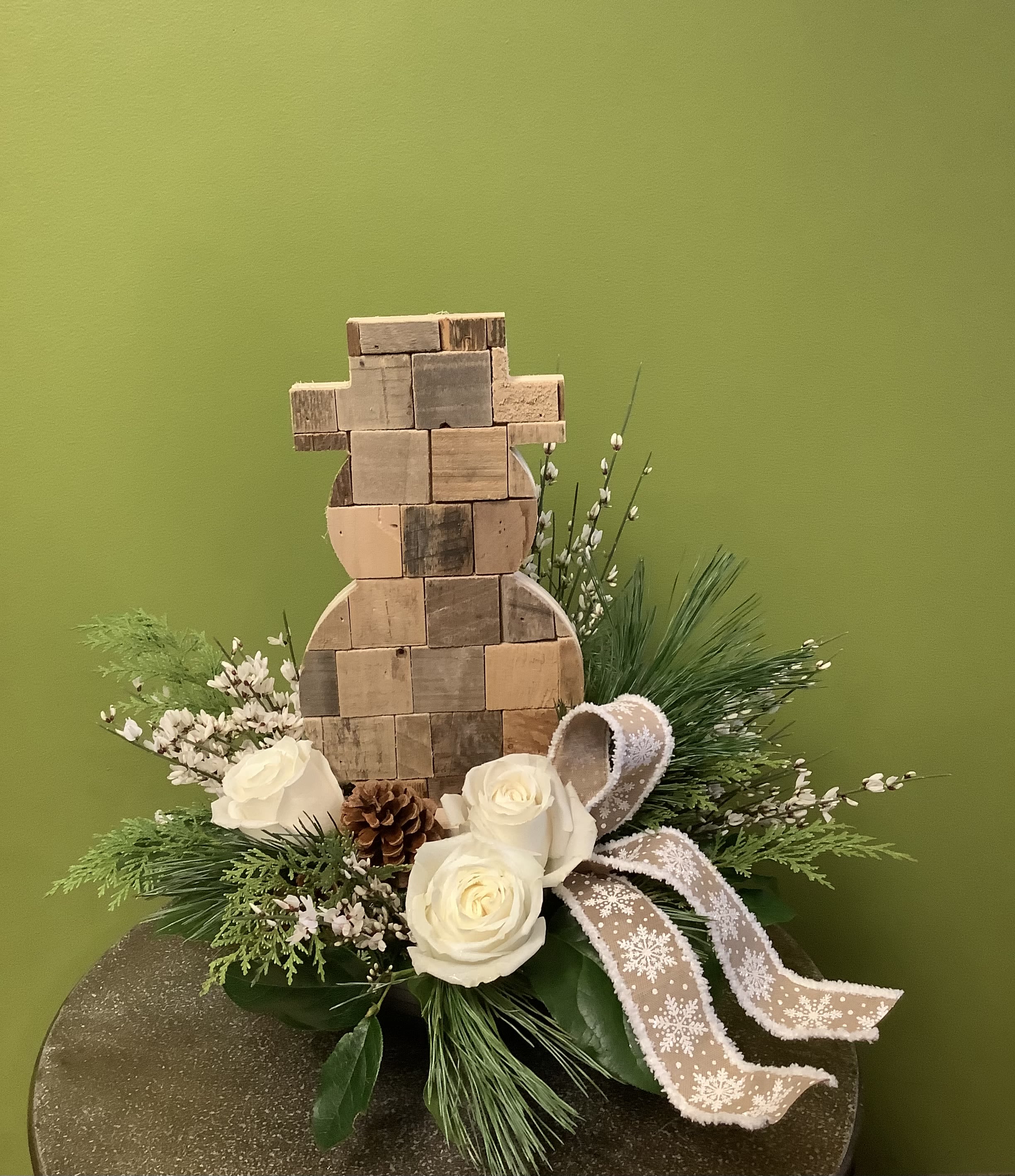 Rustic Winter Snowman - This cute wooden snowman is surrounded by winter foliage, white roses, pinecones, and festive ribbon! A perfect gift to send winter greetings someone special!