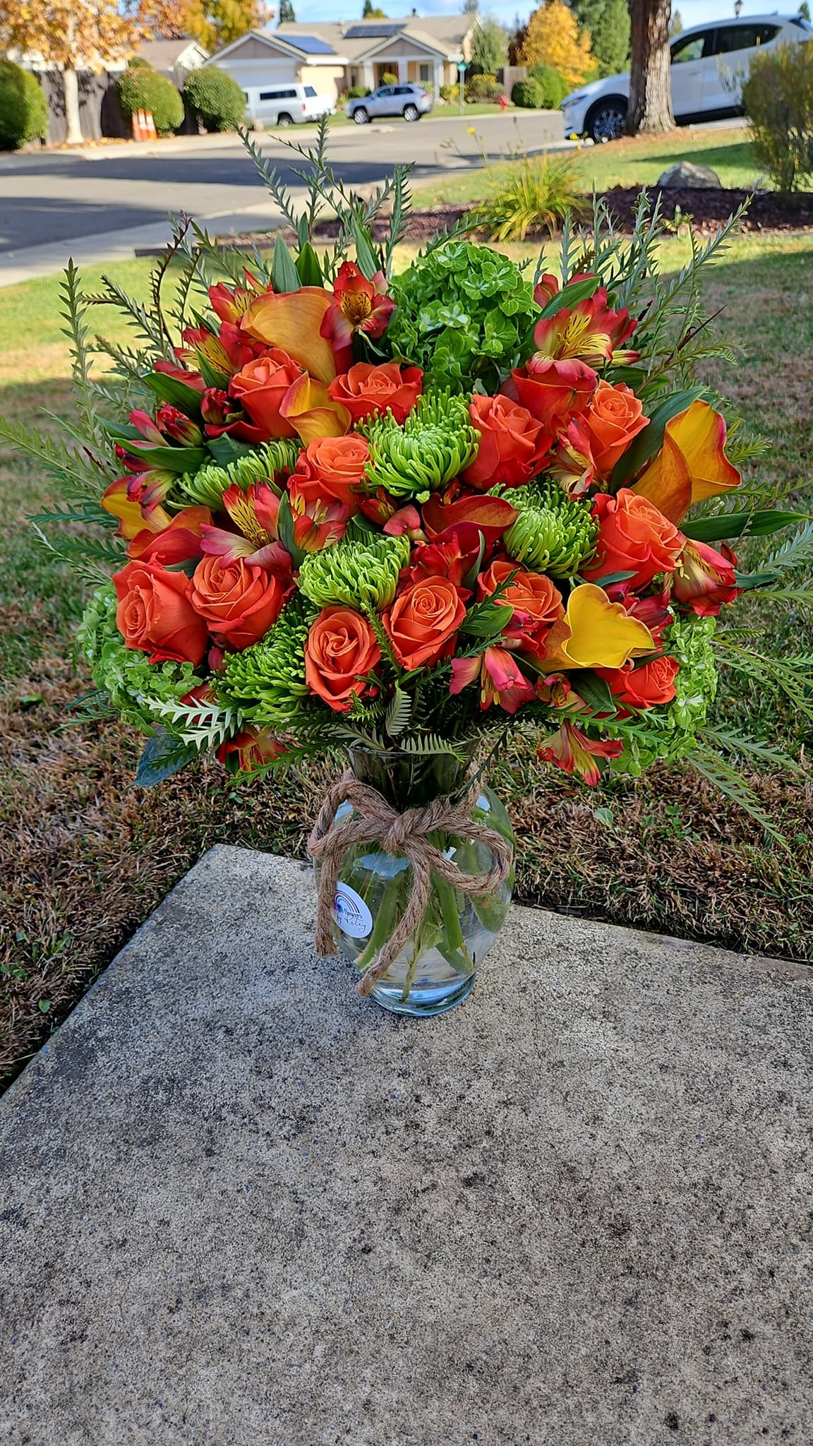 Katey's Orange Delight - Freshest orange and green flowers in season with greens in a vase.