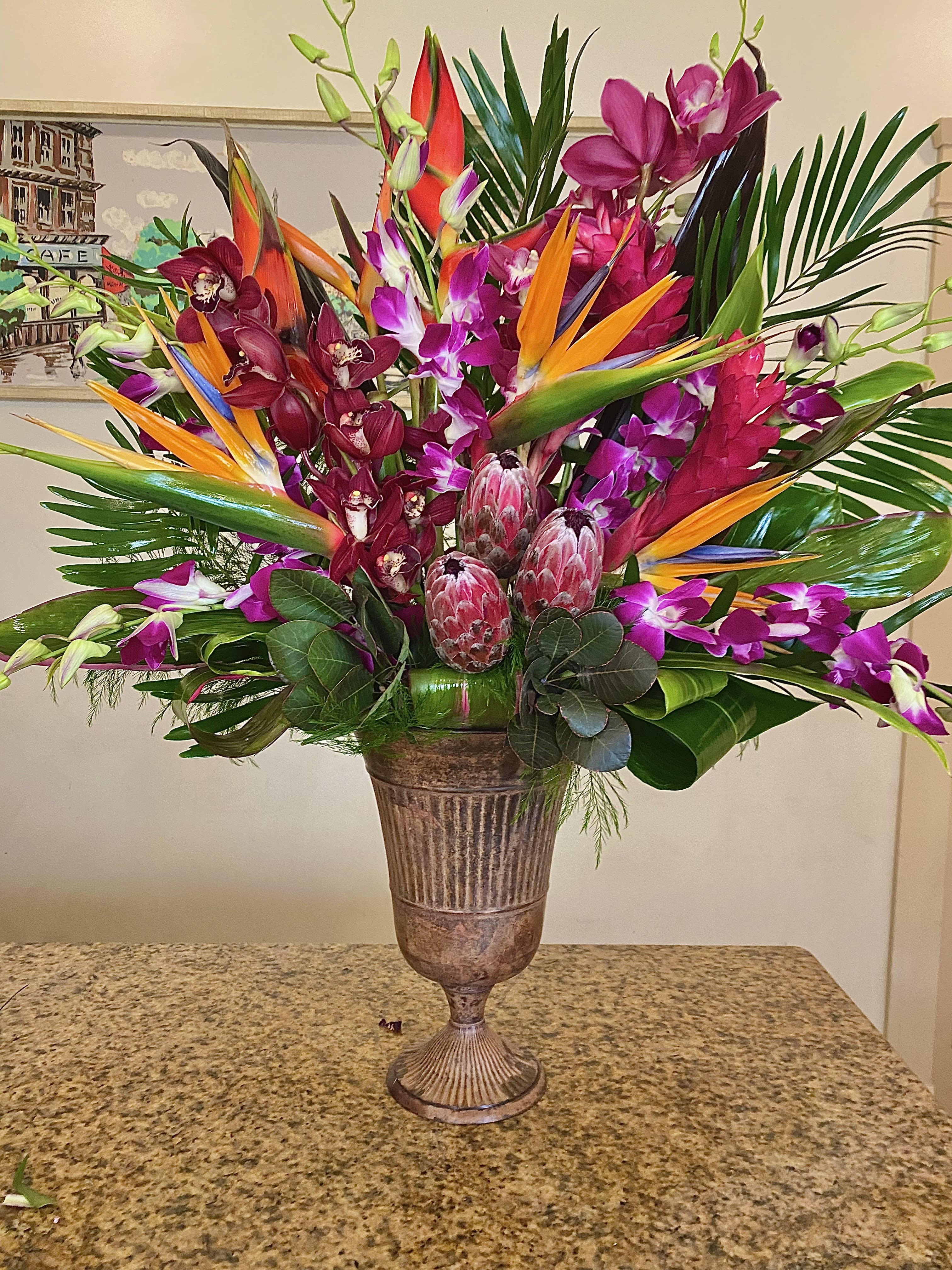 Hot Tropics - The ultimate in exotics! Tropical flowers abound with protea, heliconia, dendrobium orchids, cymbidium orchids, ginger  lilys, birds of paradise, and a lush jungle of tropical greenery.  This design must be ordered by 1:30 pm for same day.