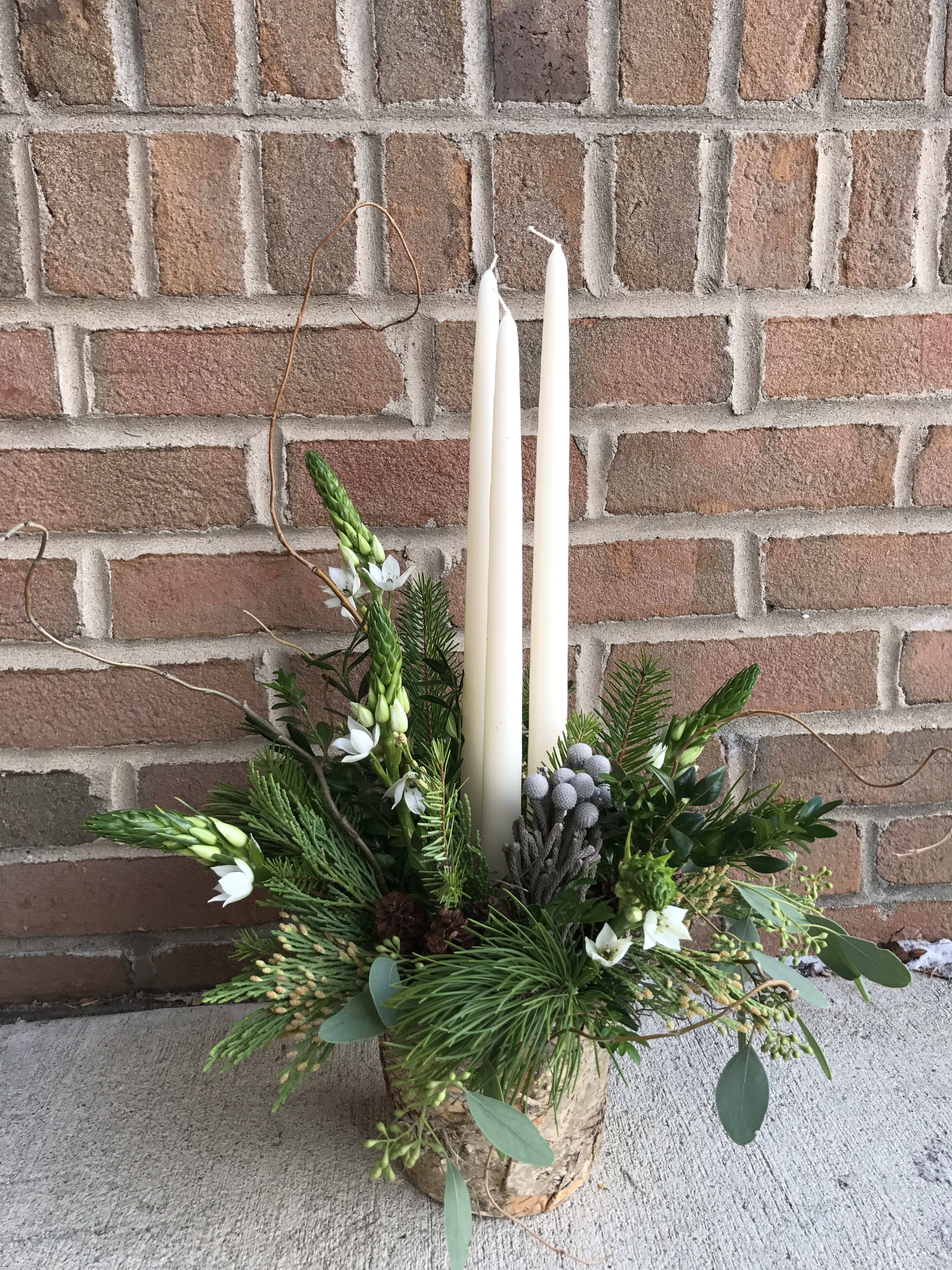 Zen Holidays - Simply perfect for that neutral and natural decor option. This design in a birch bark container features taper candles with assorted foliage, berries and a few accent blooms.