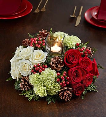 Very Merry Modern Centerpiece™ - We’ve put a truly original twist on a traditional centerpiece! This contemporary beauty features red and white roses, lime green carnations and assorted Christmas greens, hand-crafted by our expert florists with berries and realistic pinecones. At the center is a clear glass cube vase with a tea light candle inside, perfect for casting a cozy glow on the holiday festivities. A low-mounded, clustered design allows for easy conversation over the arrangement’s all-around beauty. *Our florists select the freshest flowers available, so colors and varieties may vary due to local availability *Hand-crafted centerpiece features fresh red and white roses, lime green carnations and assorted seasonal greens *Glass cube measures 3"W x 3"H; comes with tea light candle *Accented by hypericum and faux pinecones *Arrangement measures overall approximately 12"D