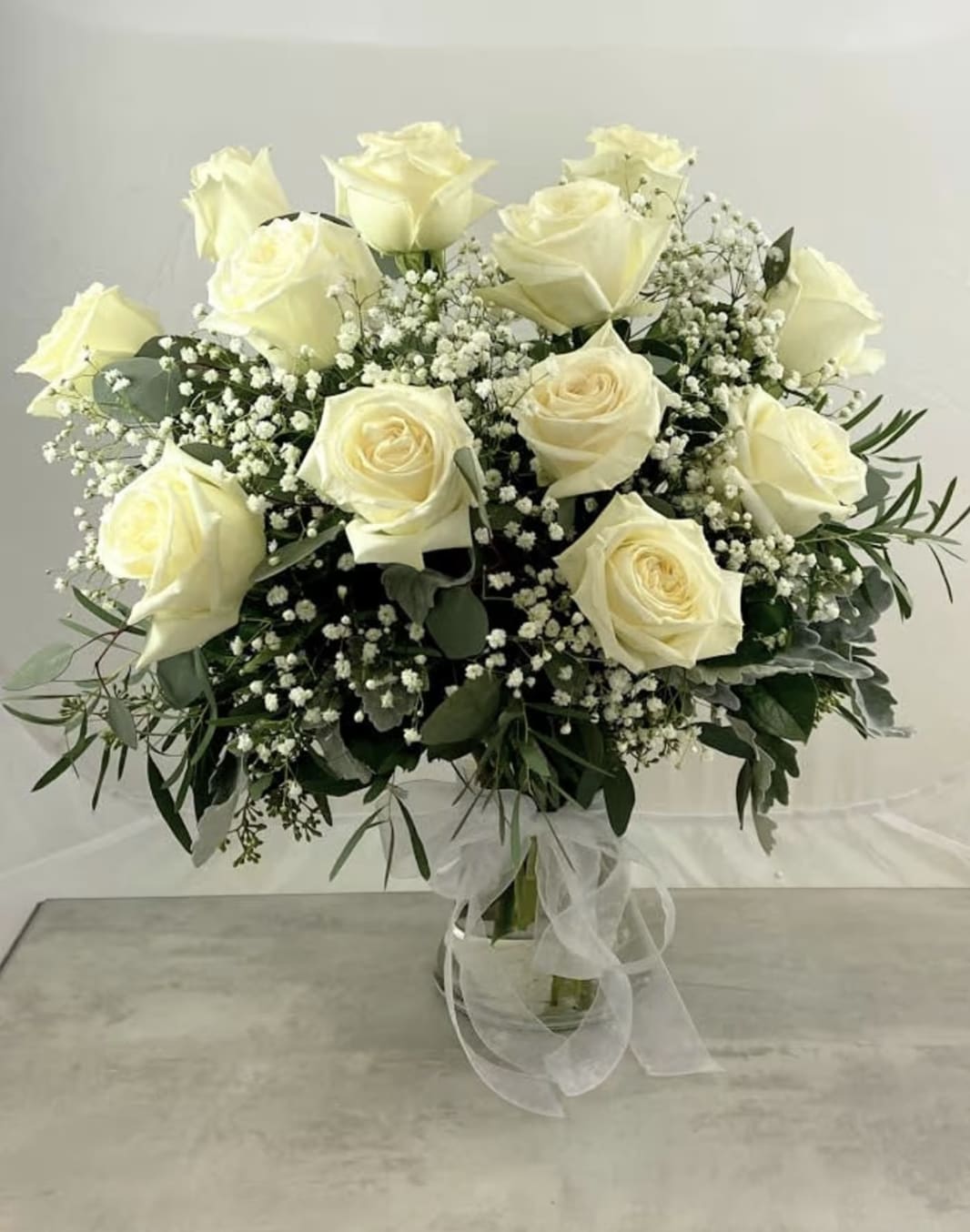 WHITE ROSES - Arranged in a clear glass vase with babies breath and greenery. 