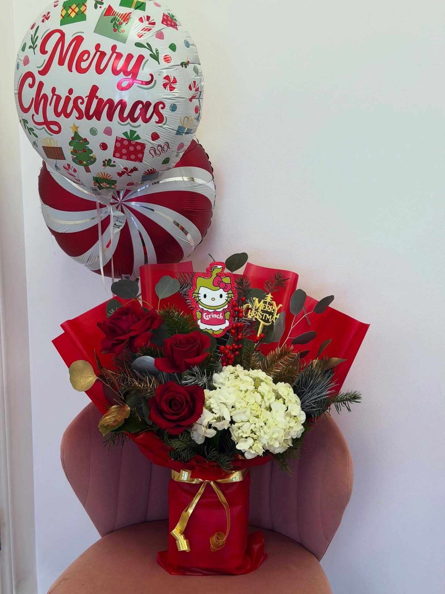 Christmas Bloom Deluxe - Celebrate the holiday season with Christmas Bloom Deluxe, an elegant floral arrangement designed with fresh red roses, white hydrangea, and seasonal greenery, finished with a festive “Merry Christmas” balloon.  This arrangement is wrapped in premium wrapping paper with a fresh floral foam base, helping keep the flowers hydrated and fresh for longer. A perfect choice for gifting, thanking, or sharing holiday cheer.