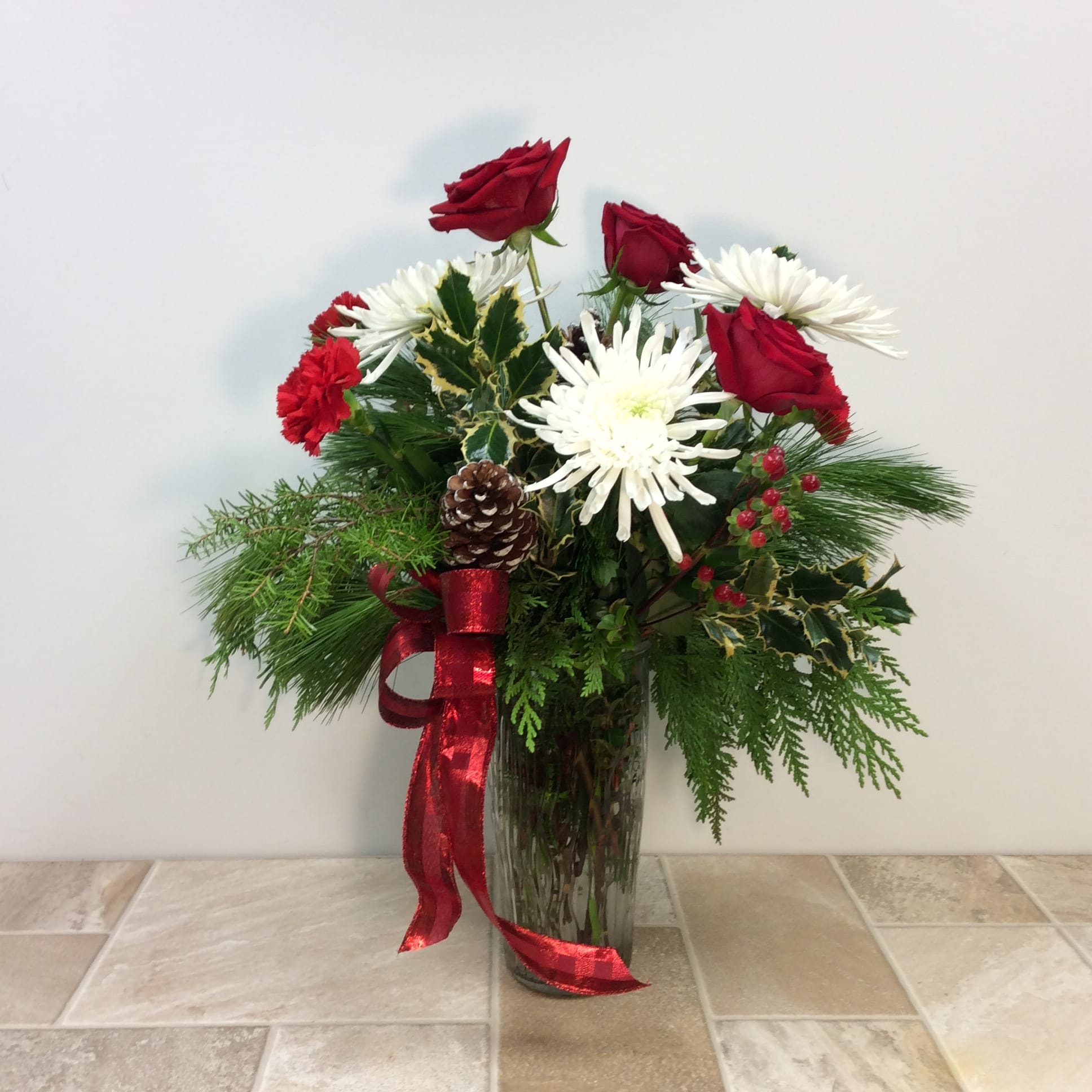 Claire - A beautiful holiday classic. Red roses and carnations along with fresh holly, evergreens, berries and white fuji mums. 
