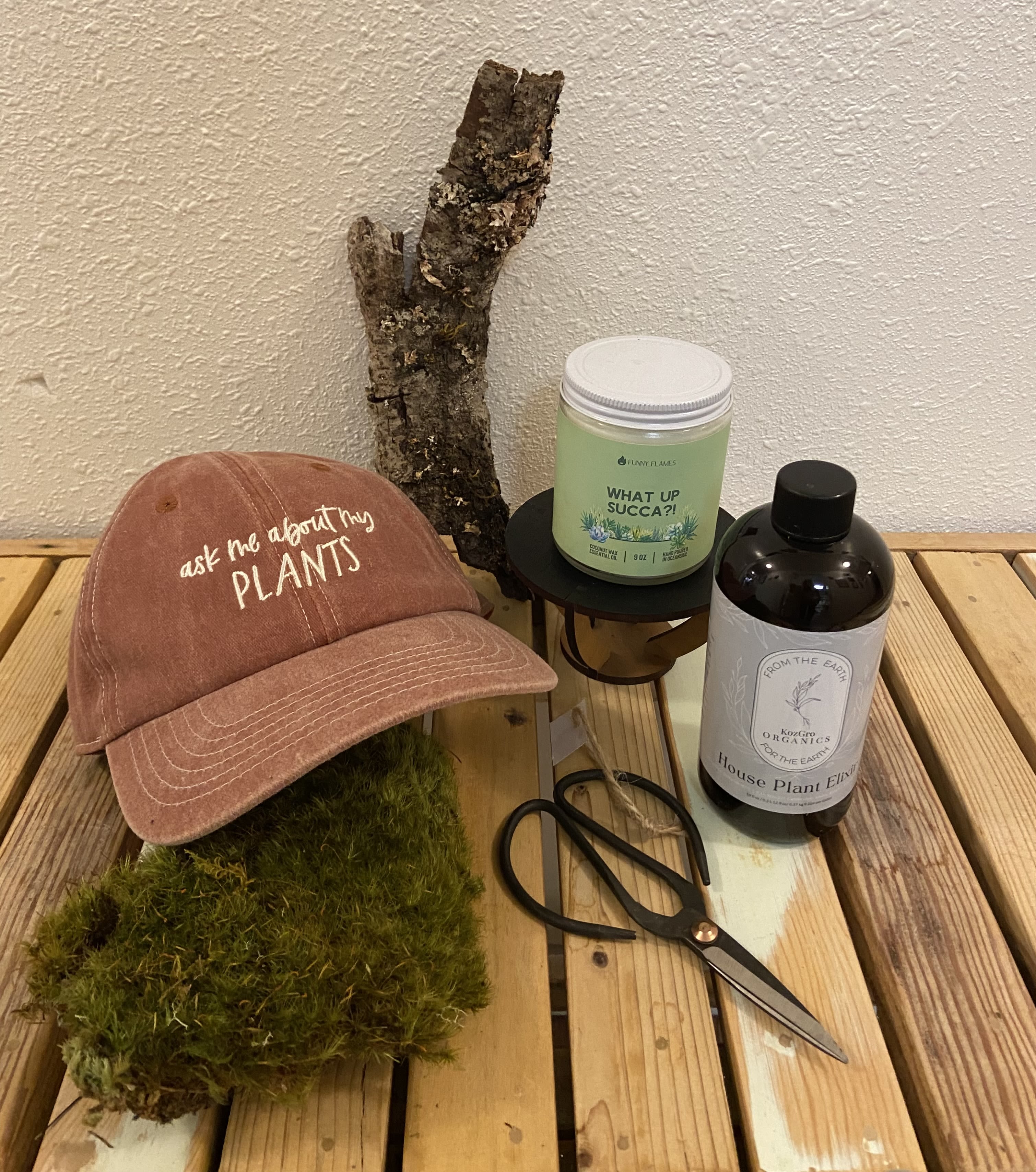 Plant Lovers Gift Set - A wonderful gift for the plant lover in your life! This gift set includes, Iron Snippers, an "Ask Me About My Plants" Ball Cap, House Plant Elixir, a funny candle, Plant Stand, &amp; Mood Moss, all tucked into a terra cotta container. 