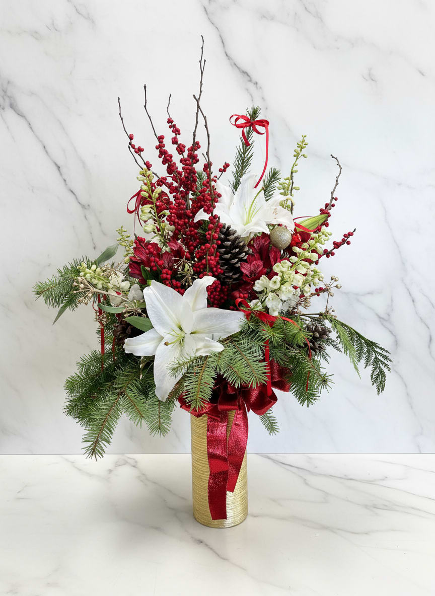 Christmas Winter berry vase - A luxurious holiday arrangement designed in a tall gold vase, featuring dramatic berry branches rising above elegant white lilies and soft white delphinium. Natural pine accents, rich green Christmas filler, and shimmering ornaments add texture and seasonal warmth, creating a striking statement piece perfect for entryways, events, or festive interiors.