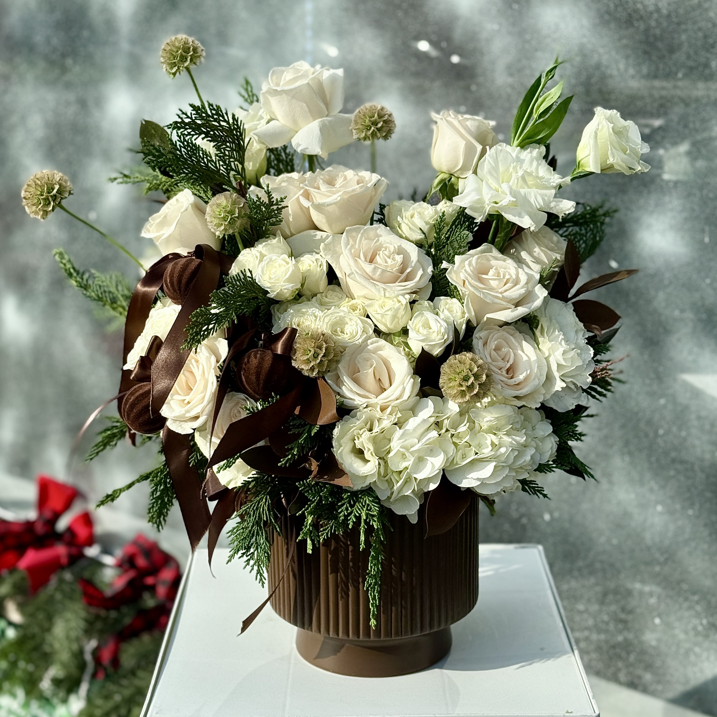 A brown winter  - Brighten any space with our Elegant Holiday Flower Arrangement! Bursting with vibrant blooms, this stunning display combines seasonal favorites with lush fillers.  Housed in a chic, reusable container, it makes a perfect centerpiece for any occasion be it a gift or a treat for yourself. Elevate your decor with this captivating arrangement that brings joy and sophistication to your home or office. Order yours today and let the beauty of flowers inspire you!