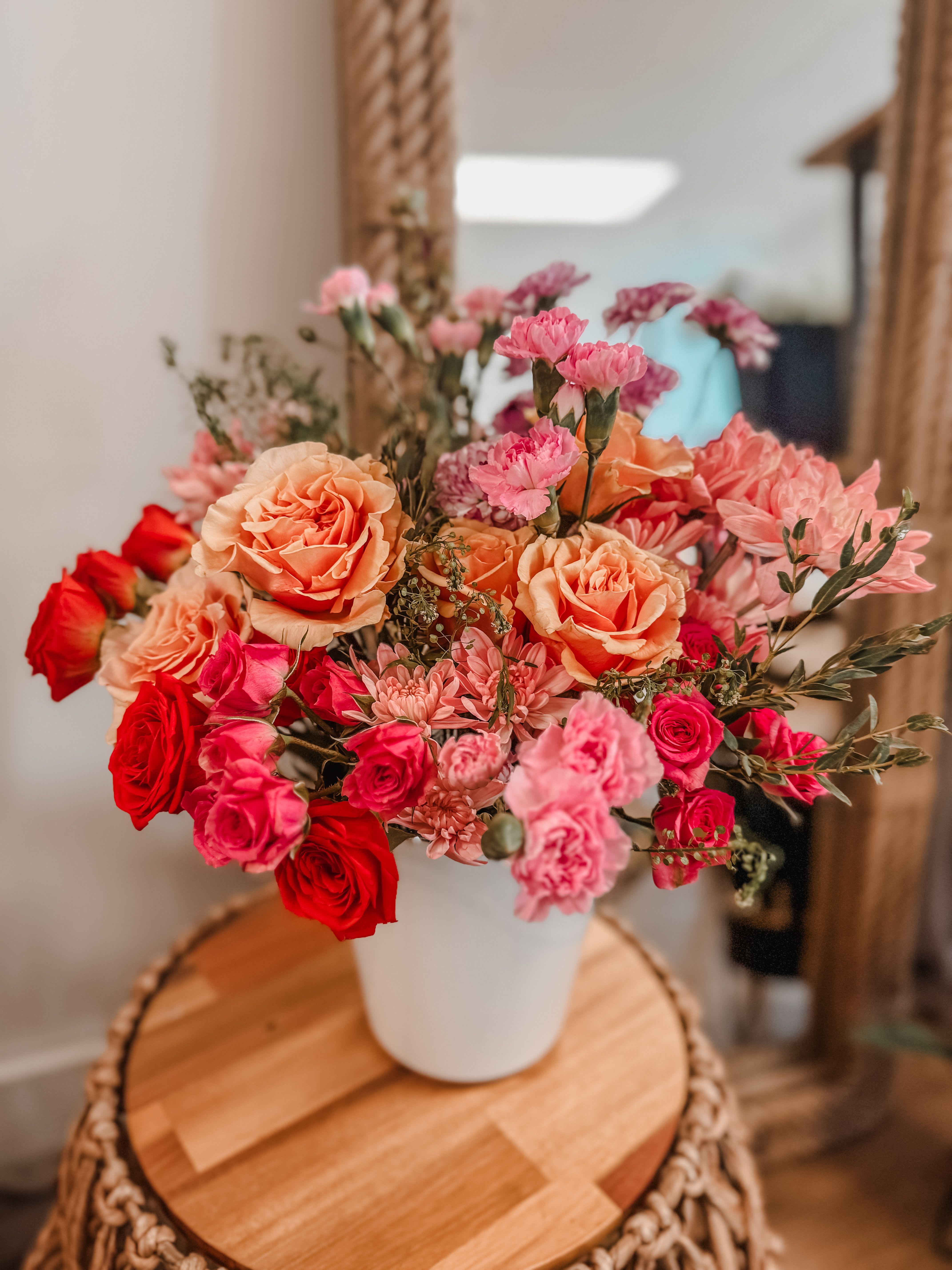 Blush Romance  - A romantic and timeless vase arrangement featuring a beautiful blend of fresh seasonal blooms in blush, peach, coral, and soft red tones. Designed with a classic garden feel, this arrangement brings warmth, elegance, and softness to any occasion.  Arranged in a modern white ceramic vase, it is perfect for heartfelt moments and meaningful gestures.  • Fresh, seasonal flowers • Handcrafted garden-style design • Arranged in a white ceramic vase • Soft, romantic color palette  Flower varieties may vary slightly based on seasonal availability, while preserving the overall color palette and style. 
