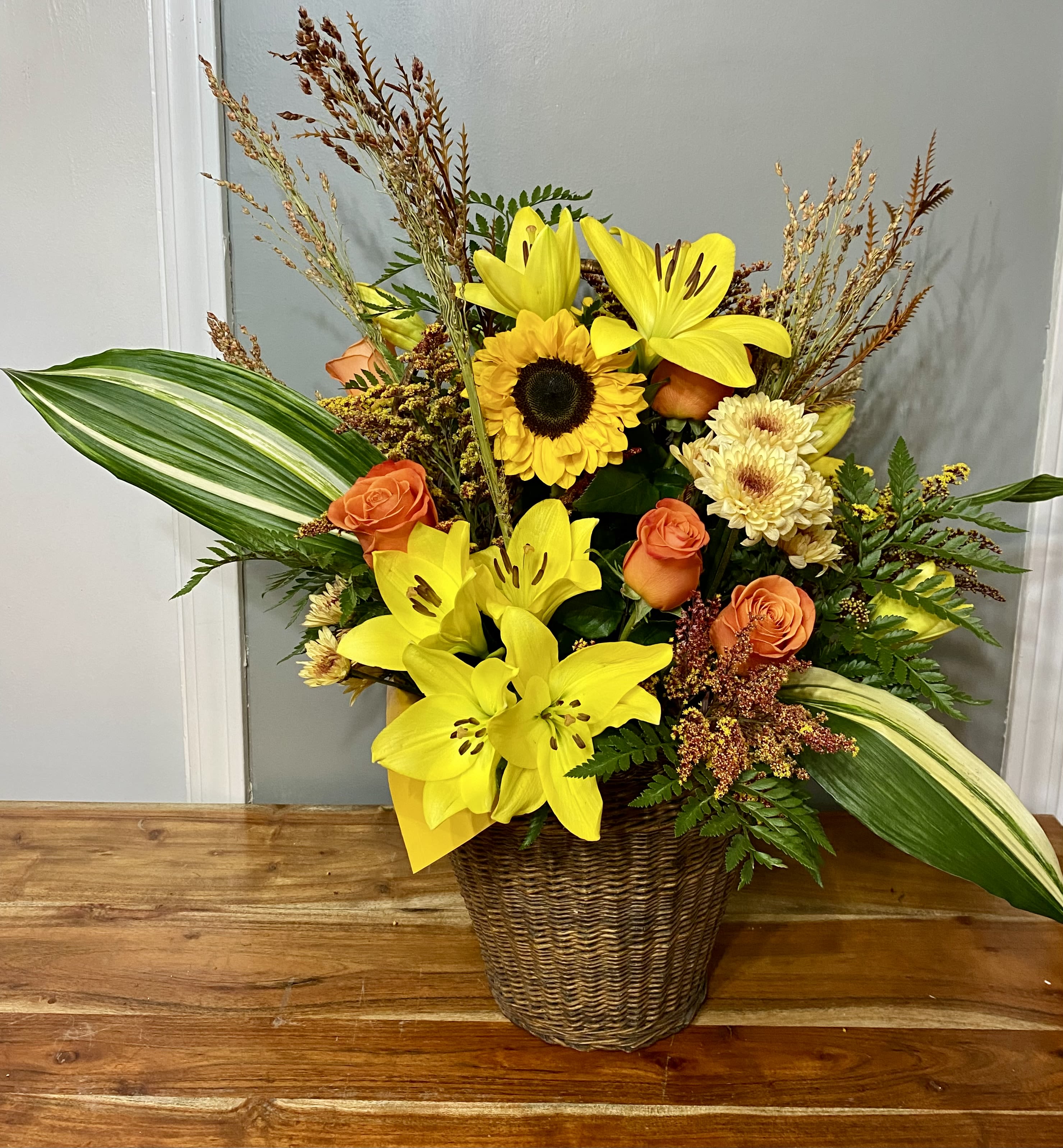 Sunshine in a Basket  - Lillies, sunflowers, mums, and roses nestled with wheat and lush greenery in a beautiful basket.