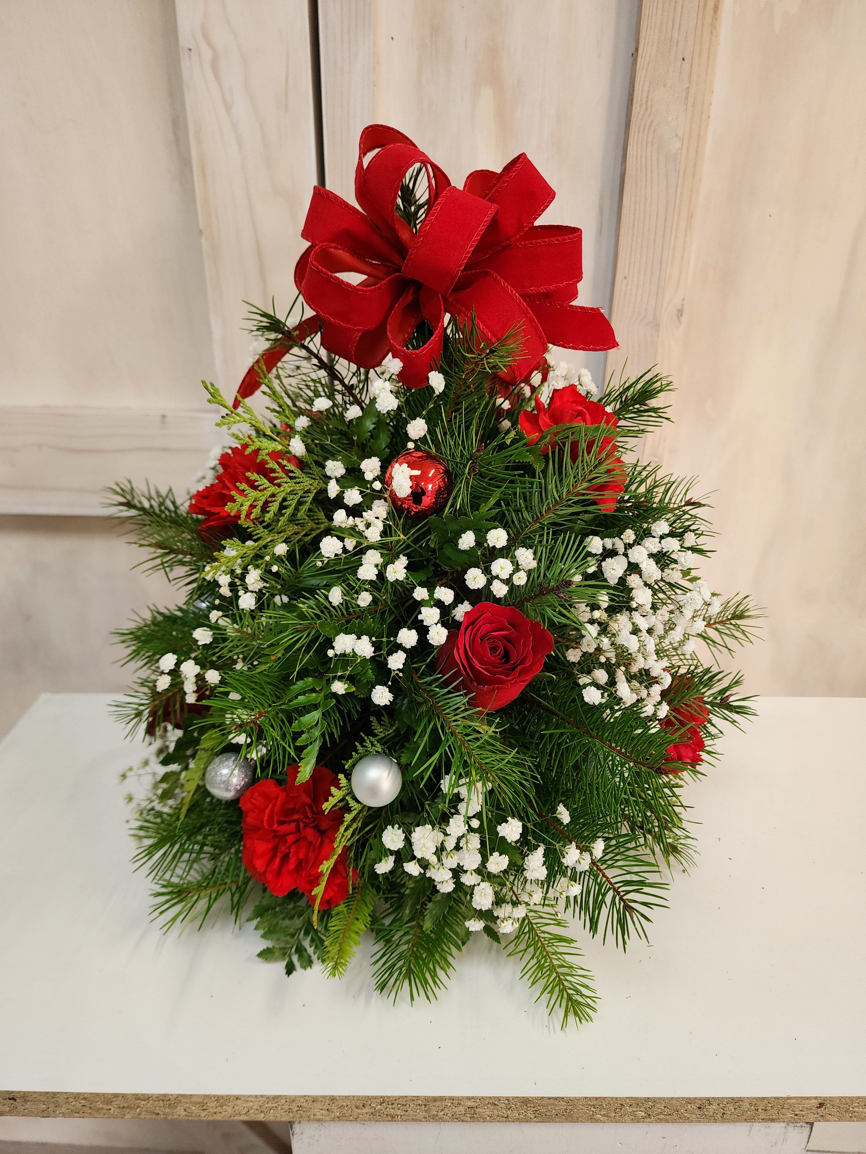 Christmas Tree Bouquet  - This tree is a beautiful mix of Christmas greens, babies breath,  roses,  carnations and ornaments.  It's a perfect holiday gift for the office or home.  