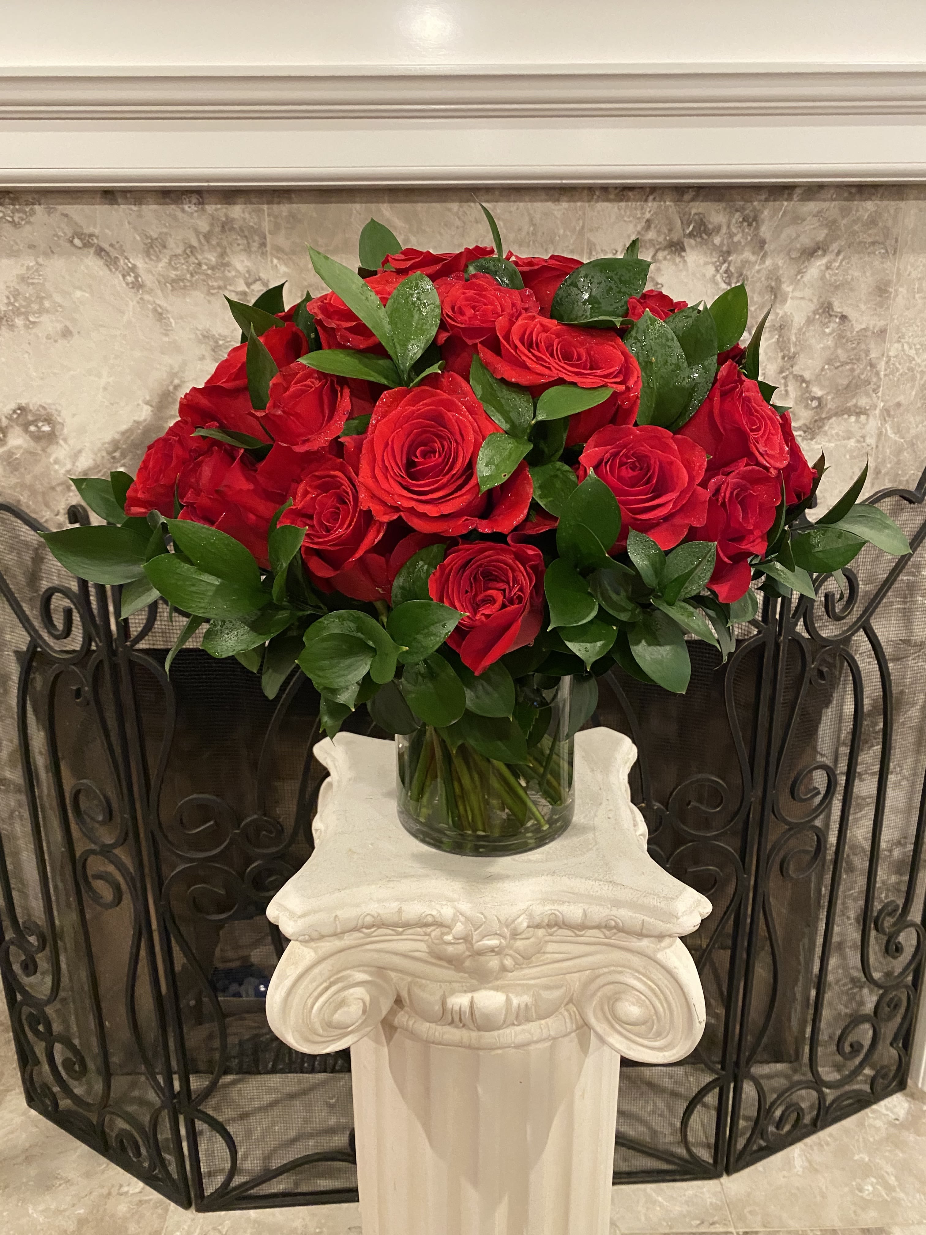 Three Dozen Red Roses With Green  On Sale - Make a bold statement with this beautifully simple design. Three Dozen Red Roses is the perfect gift for Valentine's Day, an Anniversary, or when anytime you're feeling romantic.   Arrangement Details: Three dozen red roses in a glass cylinder vase.  APPROXIMATE DIMENSIONS are 18"W X 14"H 